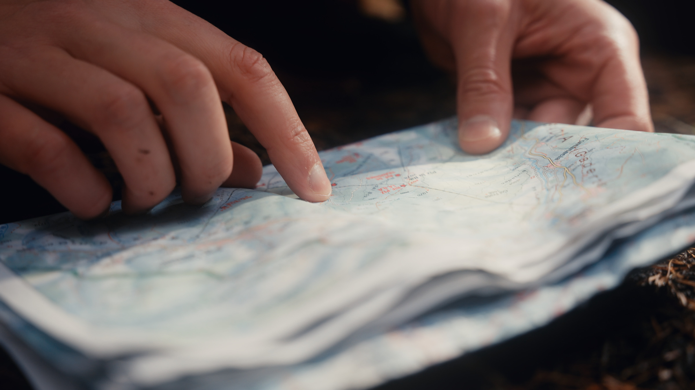 Hiker tracing a route across a folded topographic map