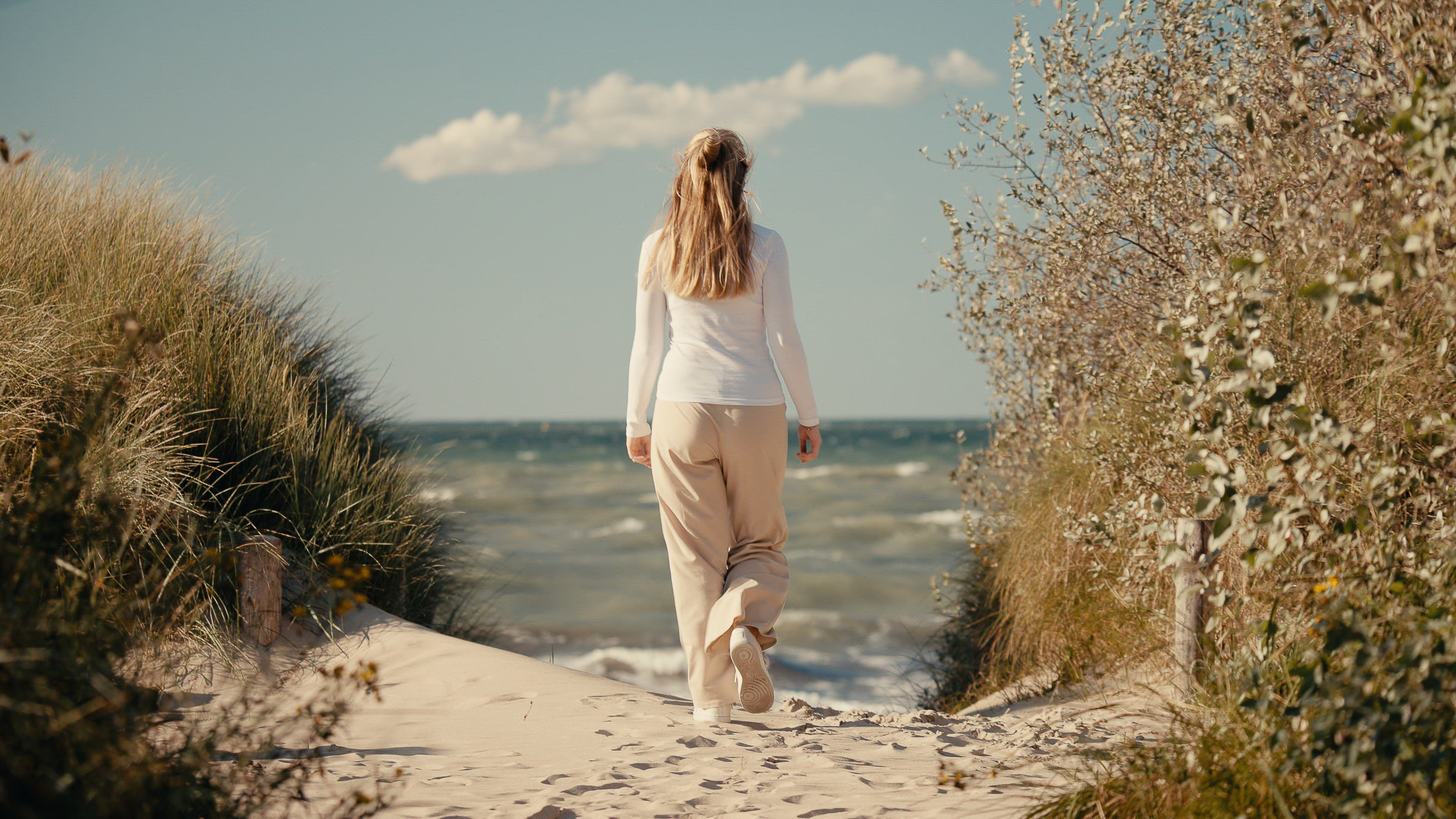 Woman walking through coastal dunes toward the Baltic Sea
