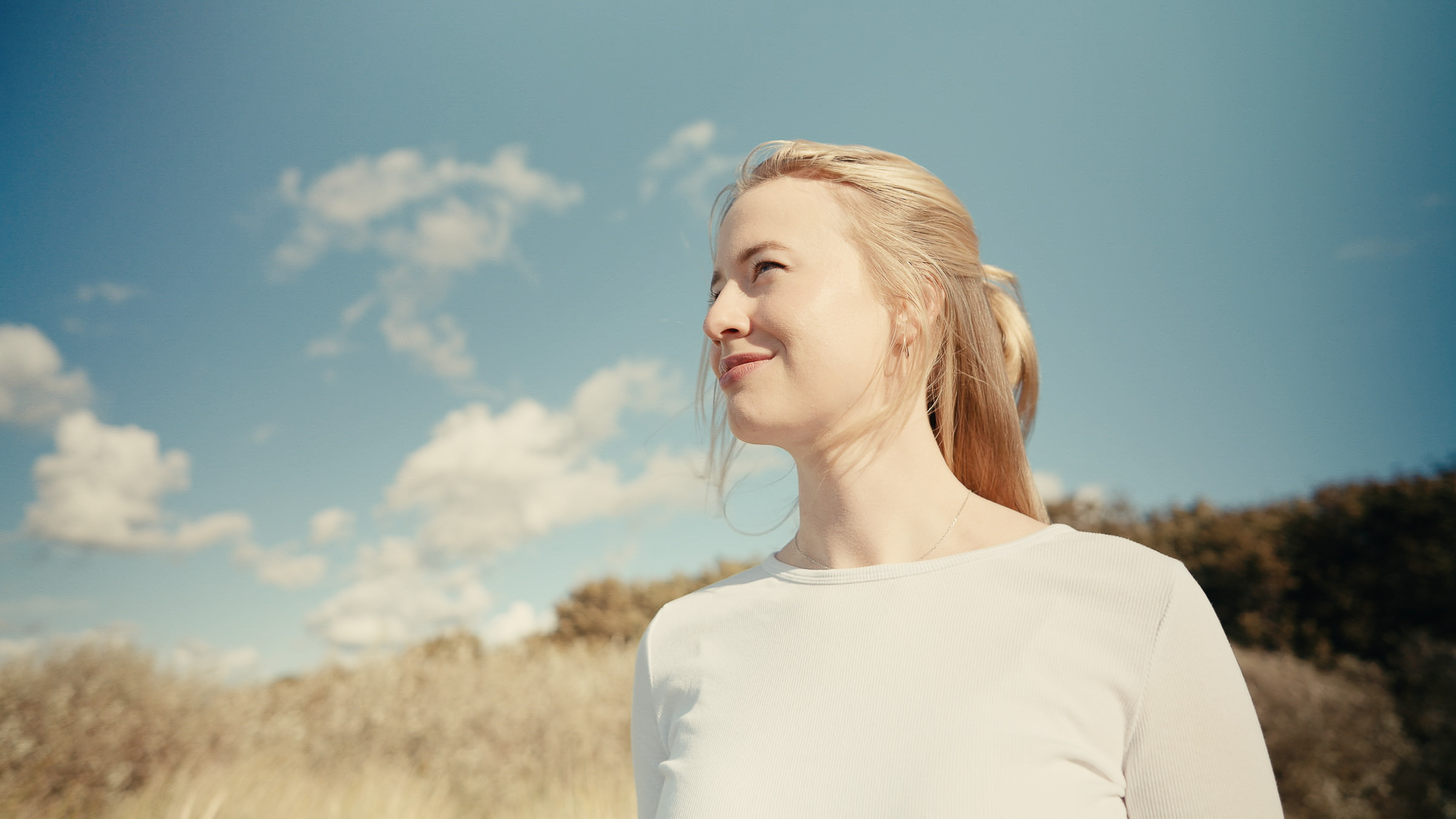 Portrait of a smiling woman among sunlit coastal dunes