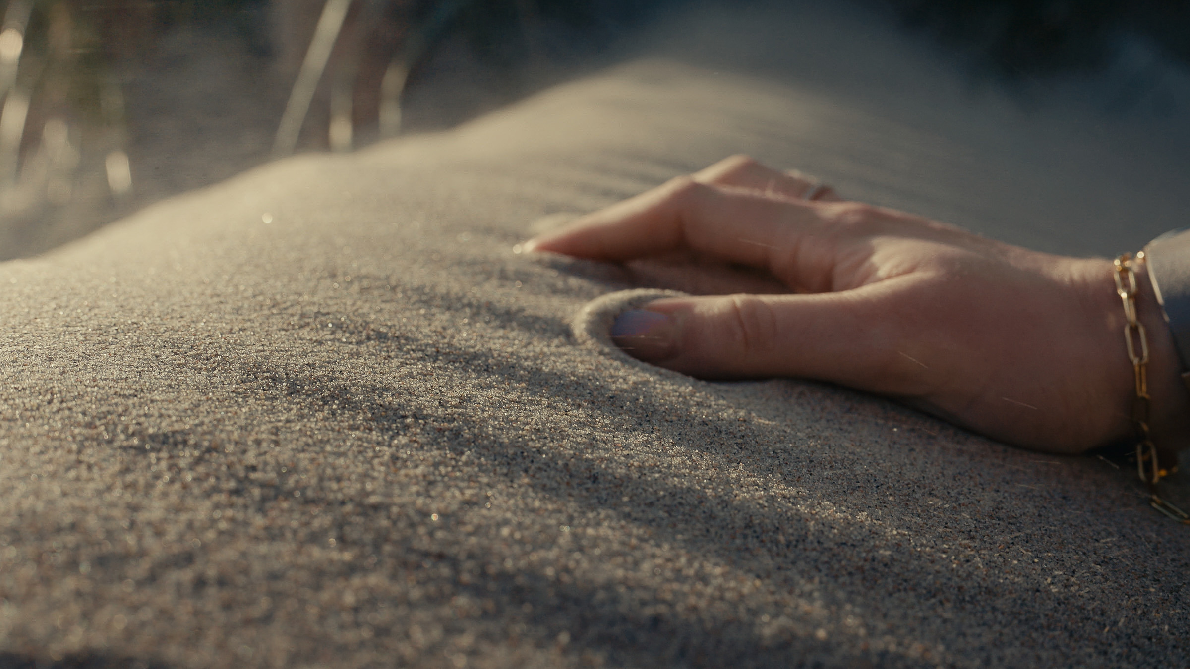 Hand resting gently on fine beach sand