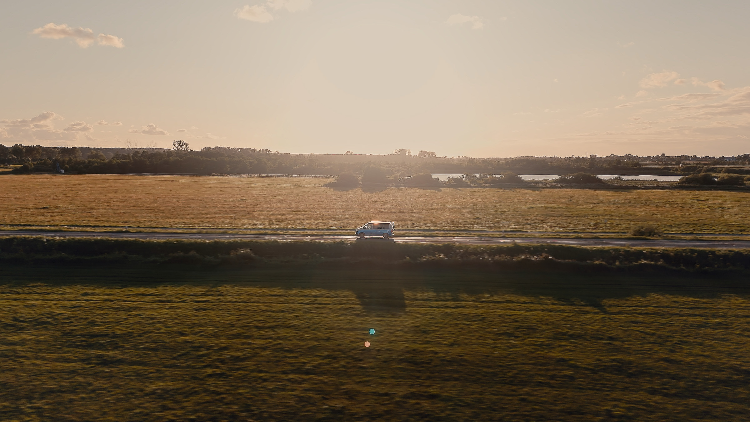 Camper van crossing open farmland in golden evening light