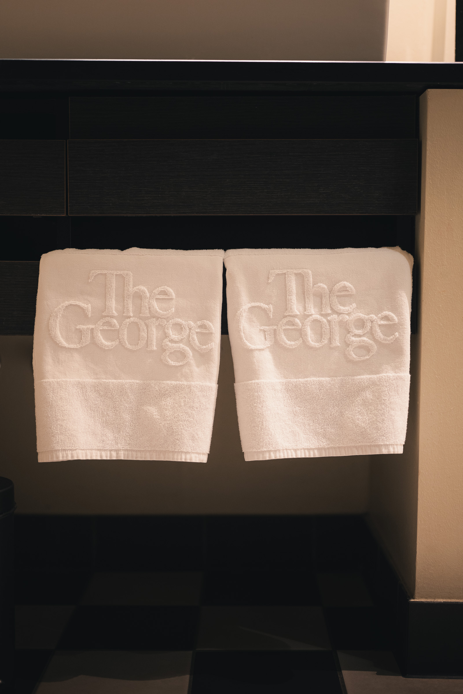 Folded towels embroidered with The George logo in the hotel bathroom