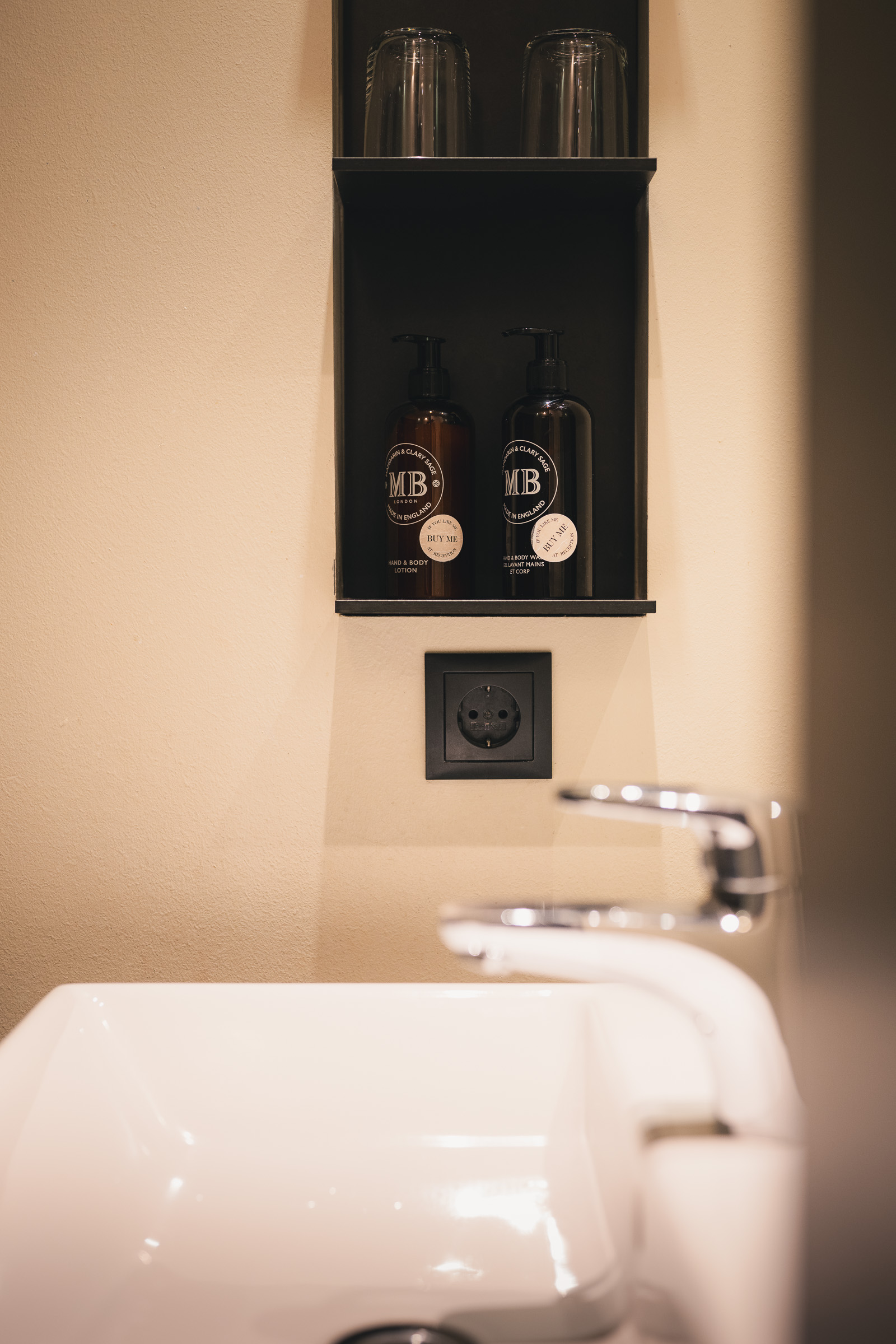 White bathtub beneath a black shelf with glass bottles at The George