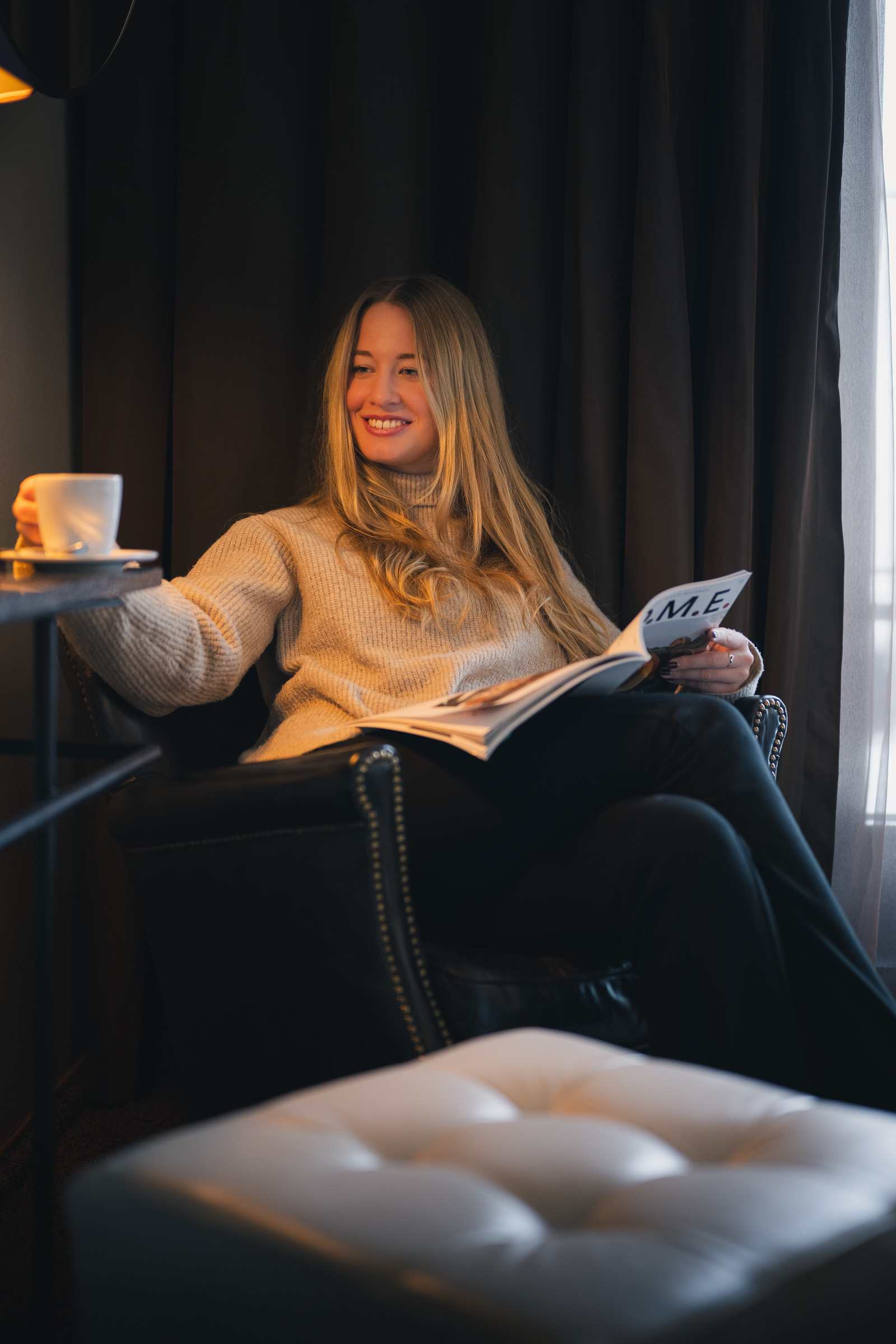Woman enjoying coffee and a magazine in an armchair at The George