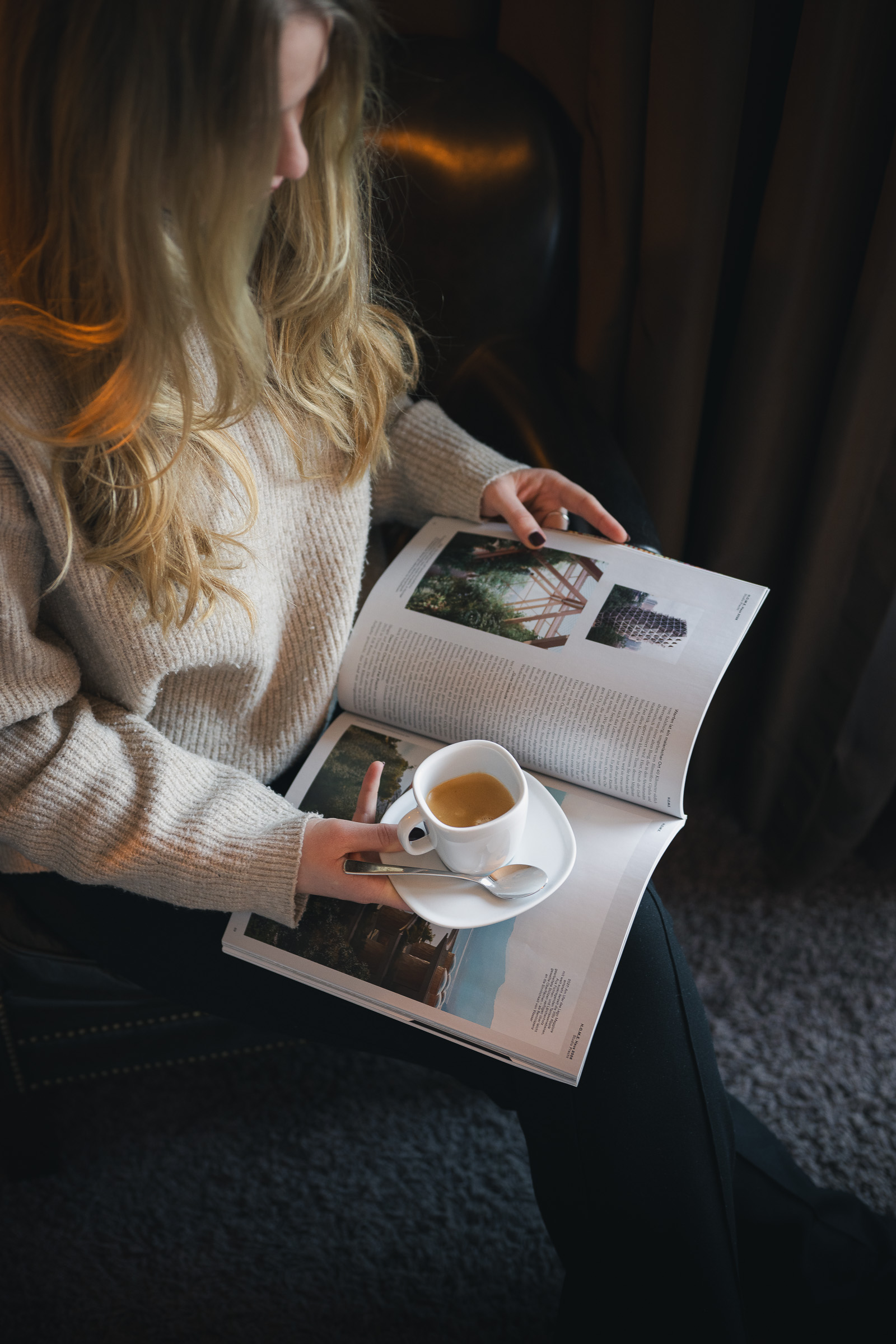 Woman reading a design magazine with coffee in her hotel room