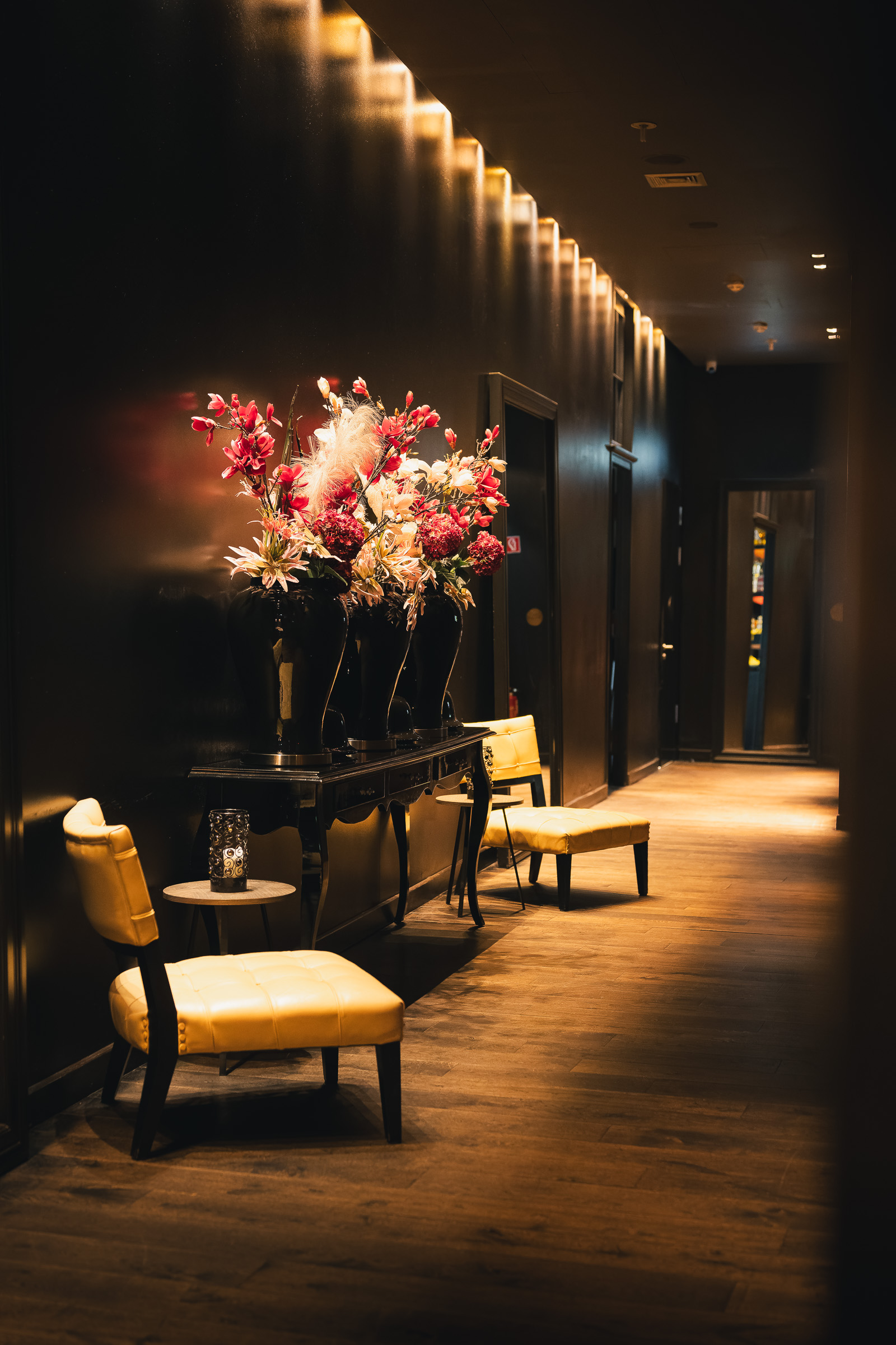 Long hotel corridor with a floral arrangement and warm wall lights