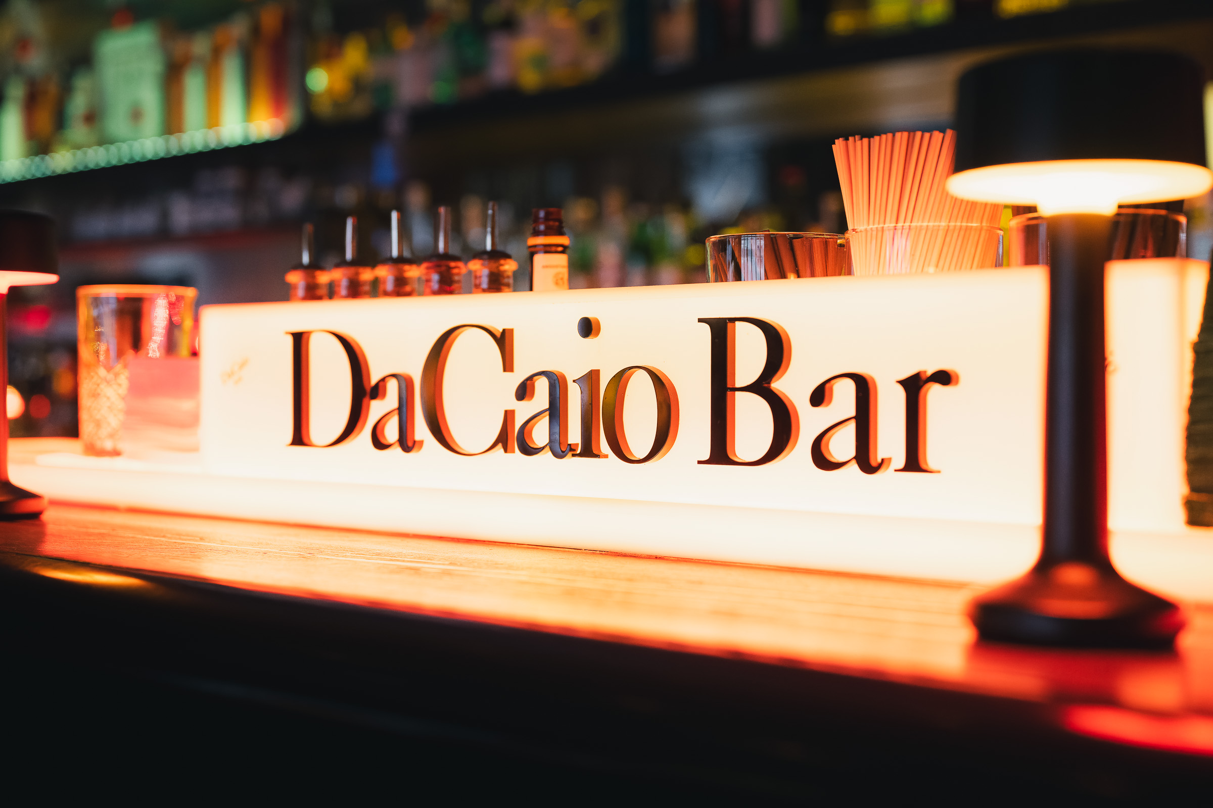 Illuminated DaCaio Bar sign in front of the hotel bar shelves