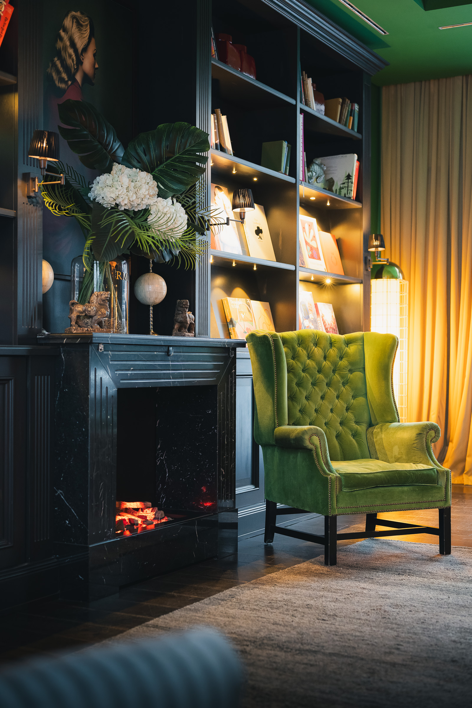 Green armchair beside a fireplace and illuminated bookshelf at The George Hamburg