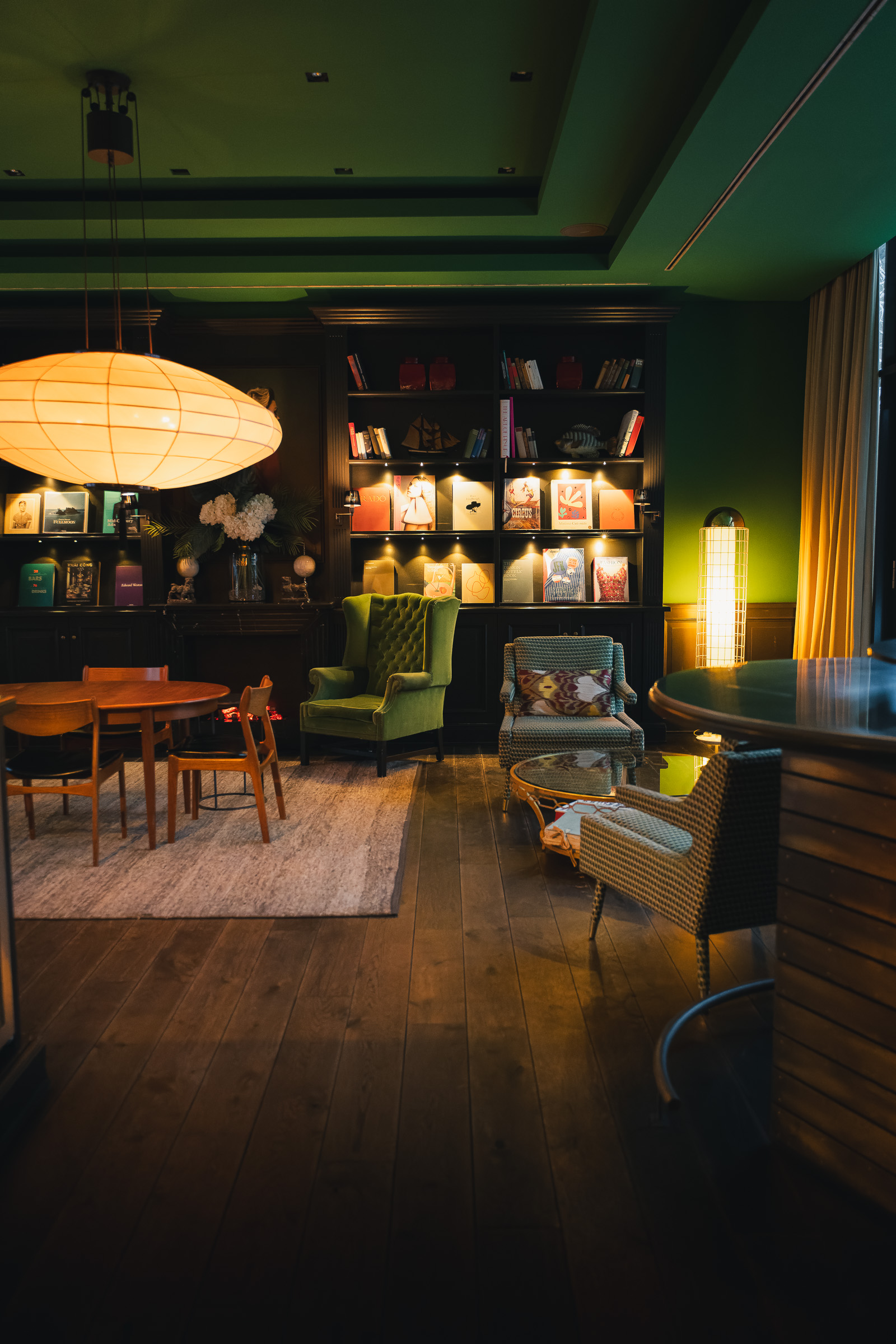 Dark green lounge with patterned chairs and illuminated shelves