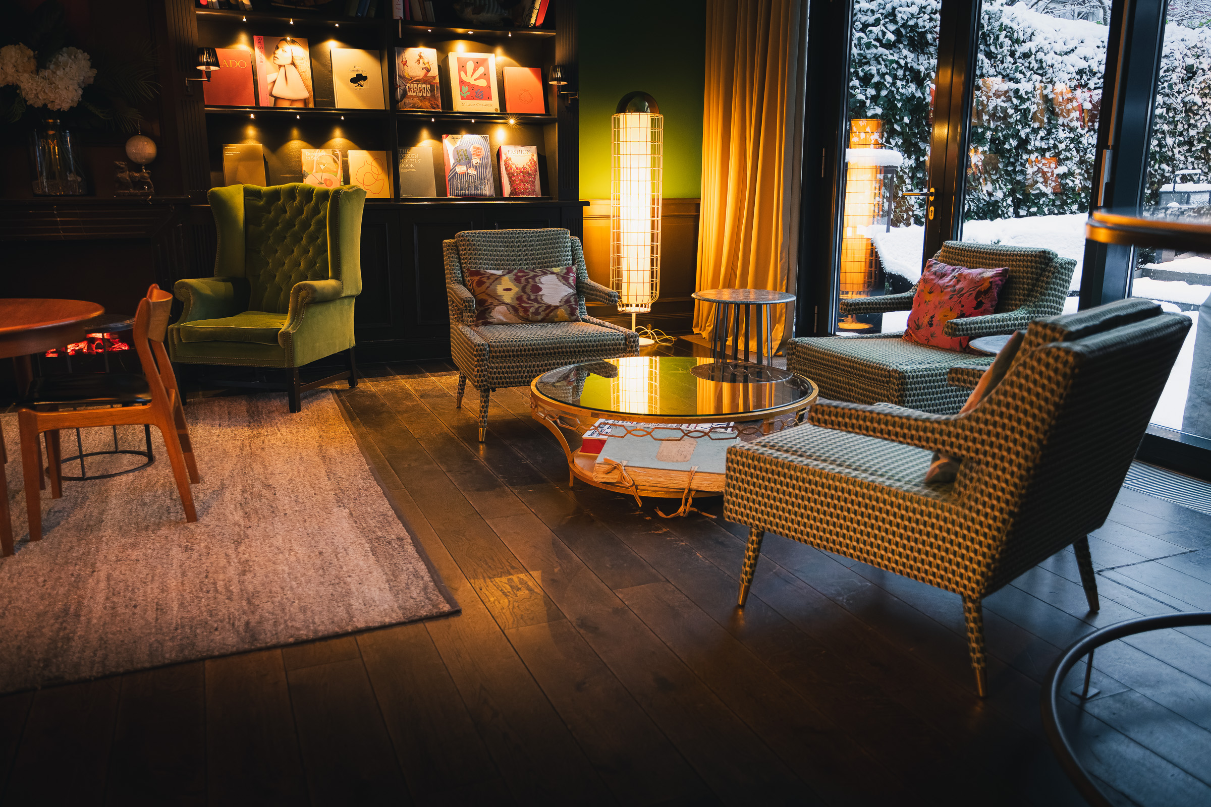 Eclectic lounge with patterned armchairs and a glowing floor lamp