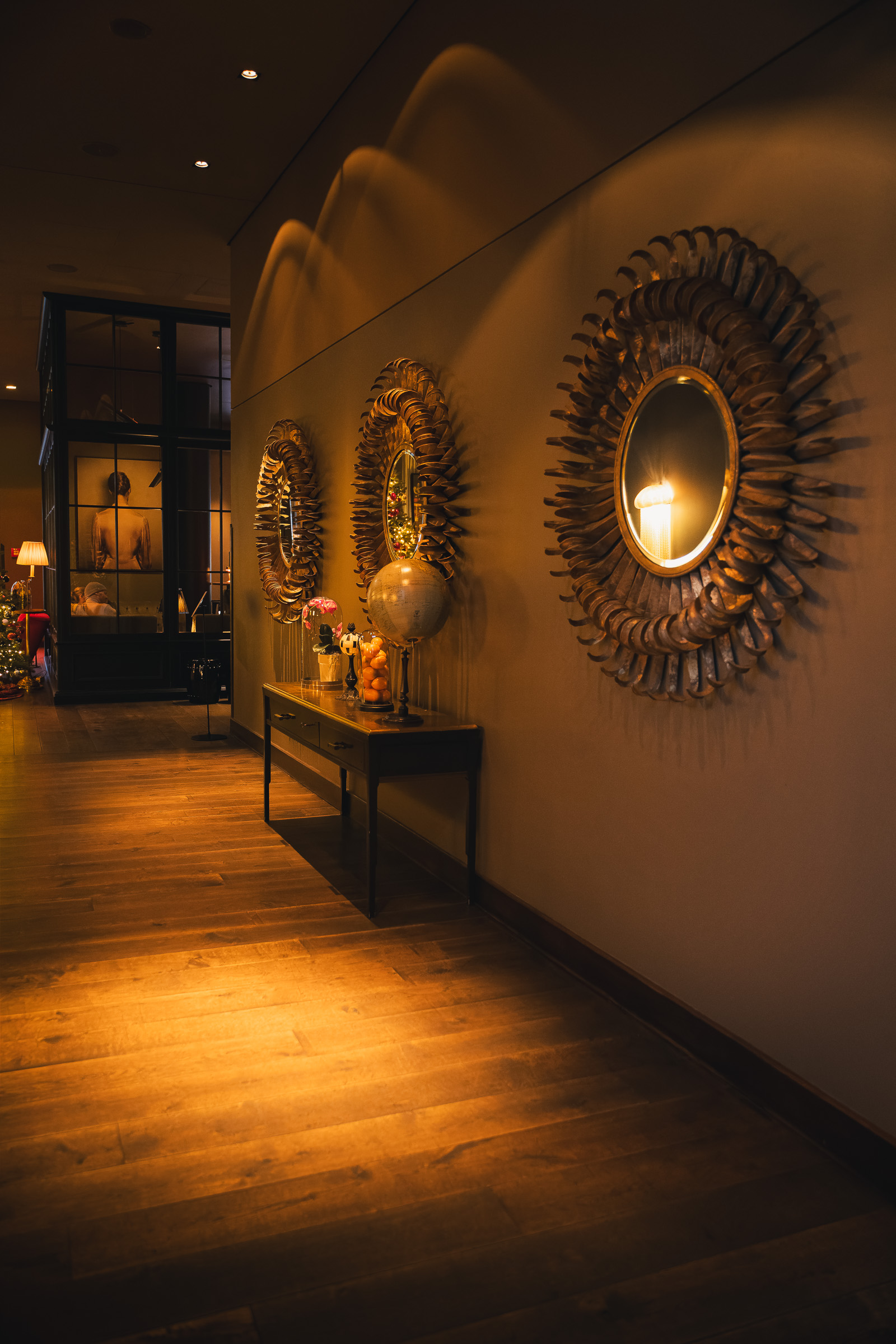 Sunburst mirrors lining a warmly lit corridor at The George Hamburg