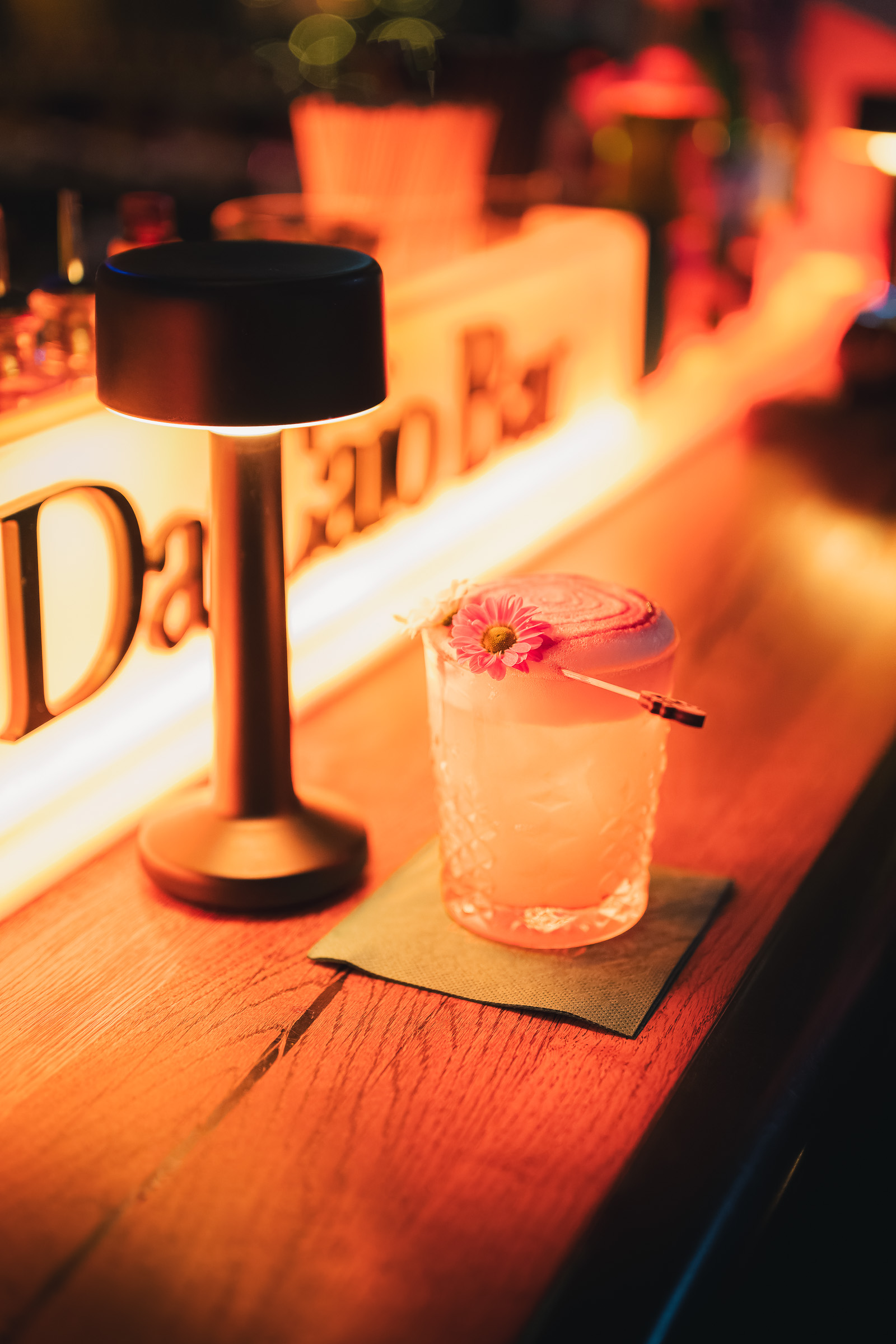 Pink cocktail beside a table lamp on the DaCaio Bar counter