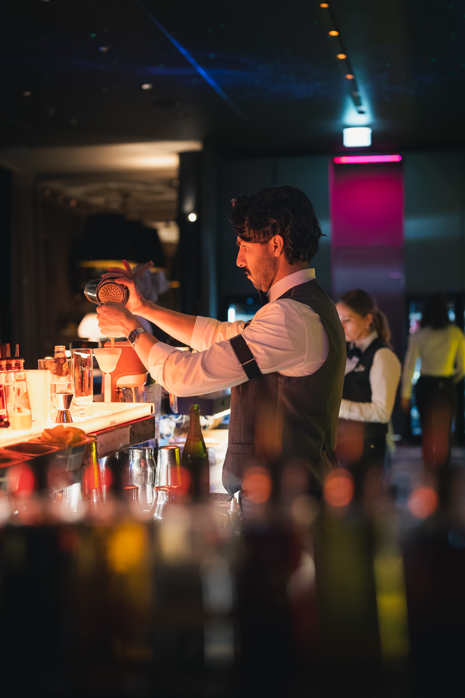 Bartender preparing drinks behind the DaCaio Bar at night