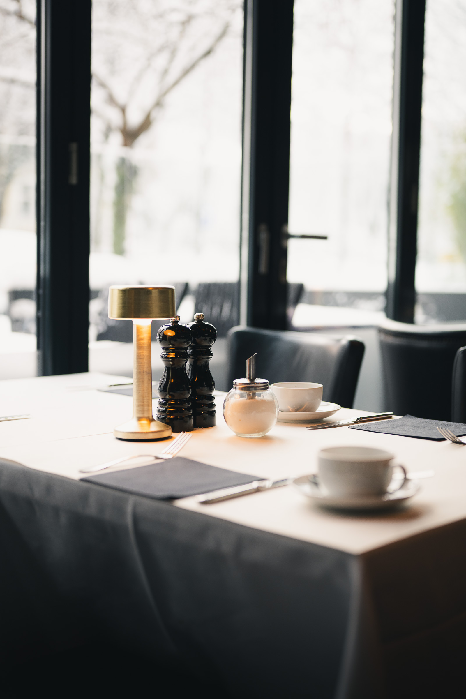 Breakfast table set with coffee and tea beside a large window