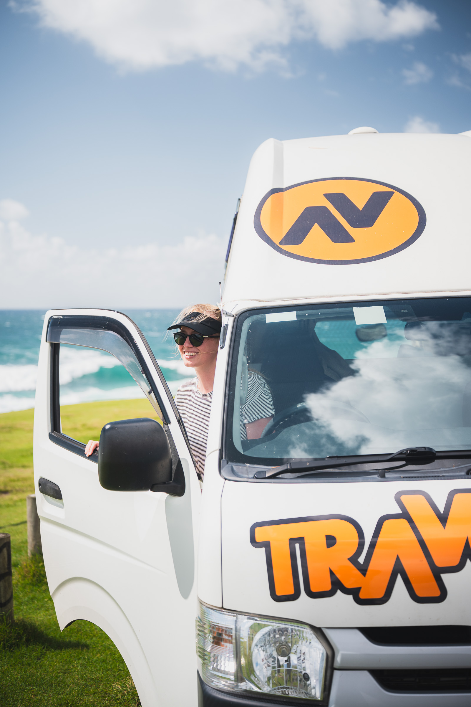 Woman standing in the open driver's door of a Travellers Autobarn camper