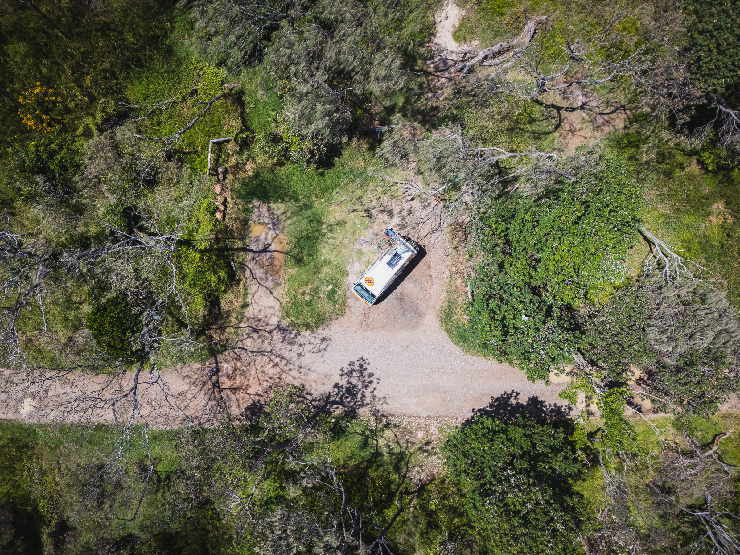Top-down aerial view of a camper parked in a forest clearing