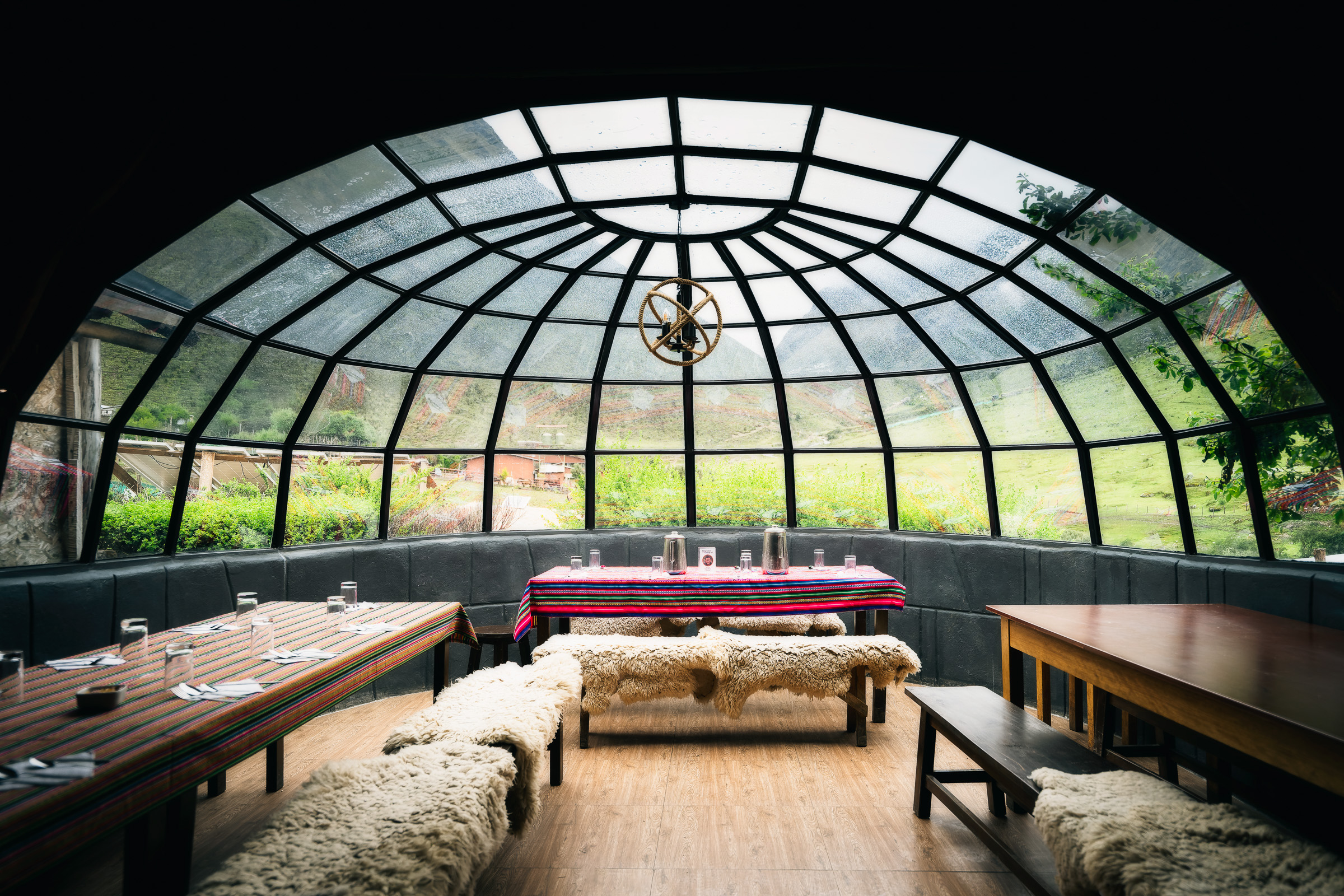 Glass-domed dining lounge with wooden tables and wool-covered benches