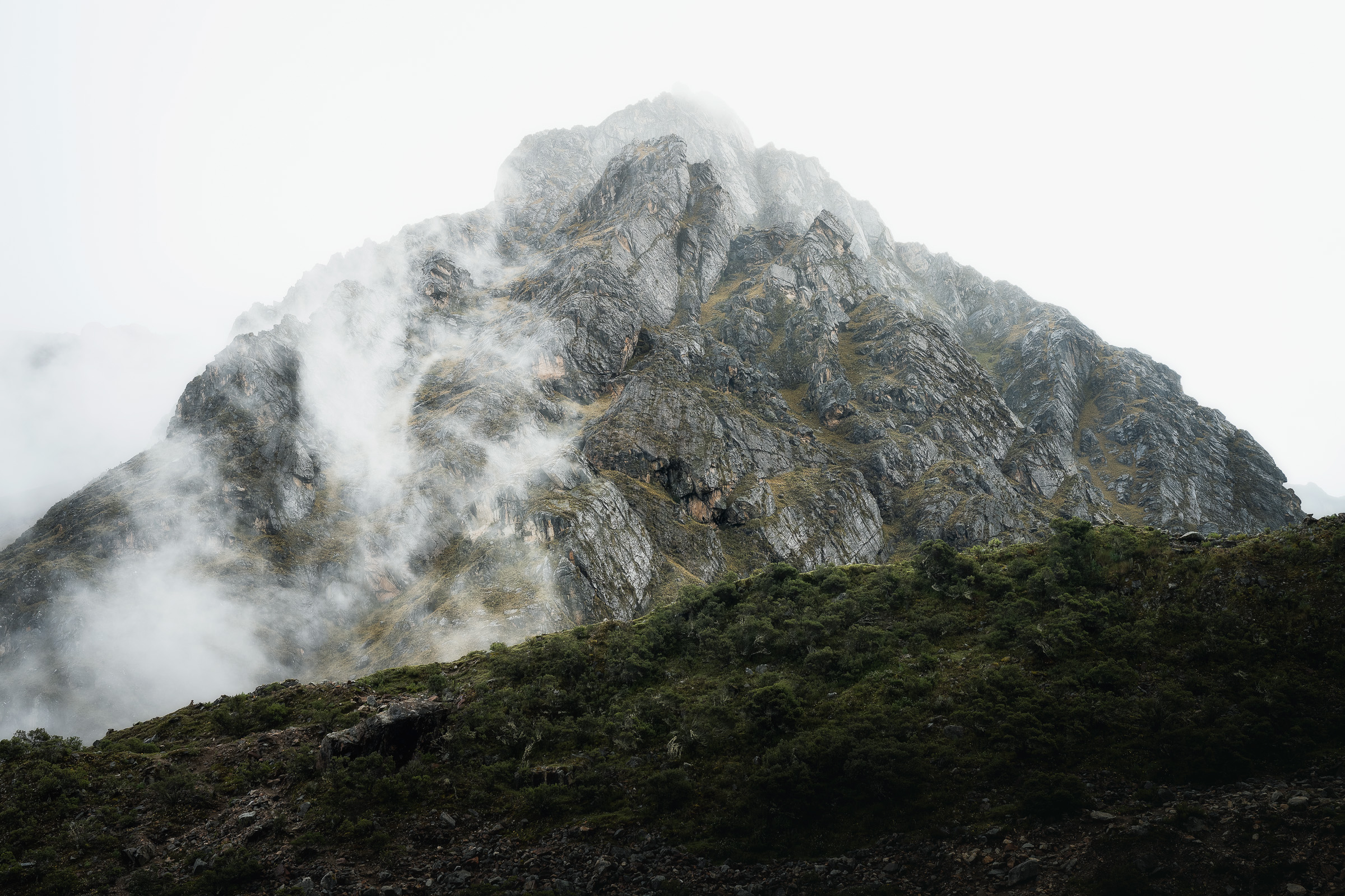 Jagged Andean peak rising through swirling mist
