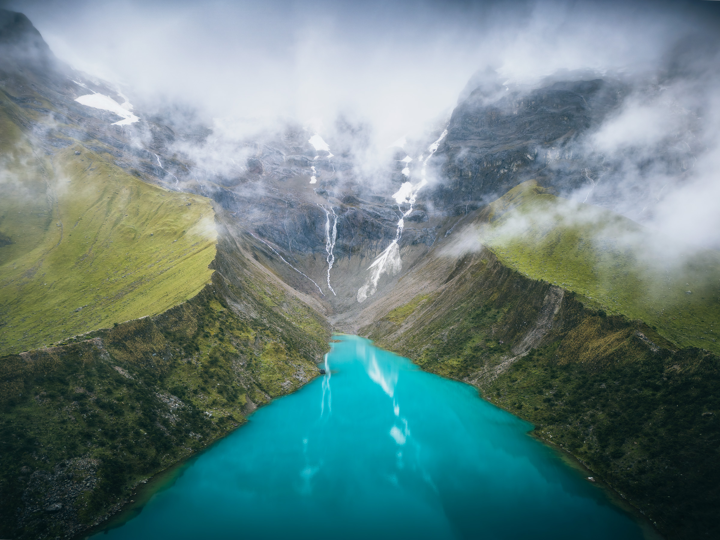 Aerial panorama of turquoise Humantay Lake framed by clouds