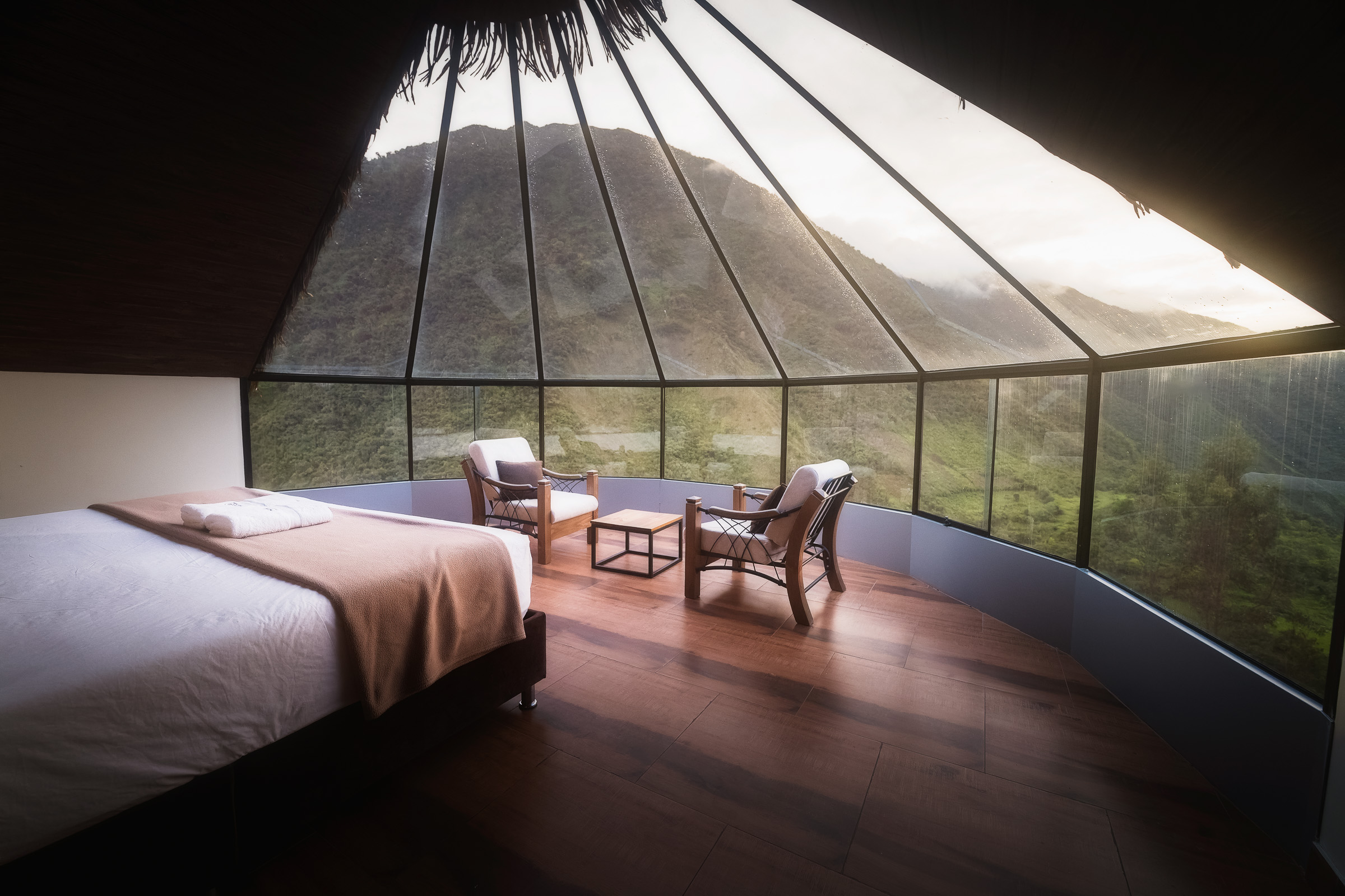 Panoramic mountain view from a glass-fronted lodge bedroom