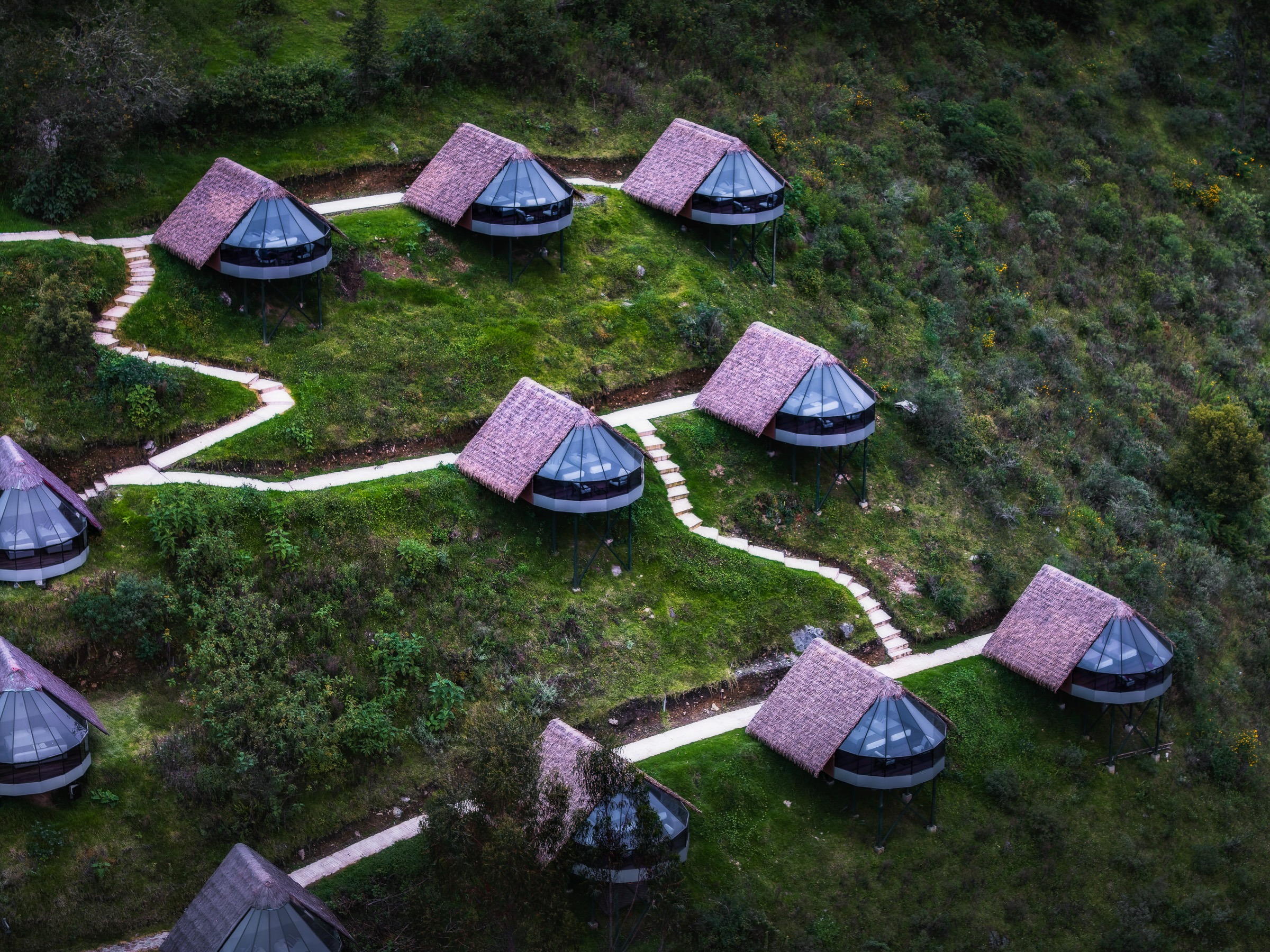 Aerial view of geodesic mountain lodges connected by winding paths