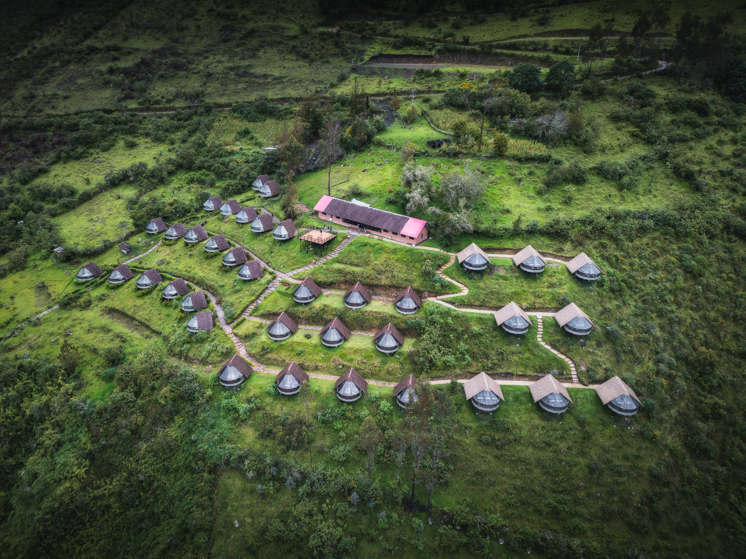 Aerial view of a trekking camp with rows of lodges in a green clearing