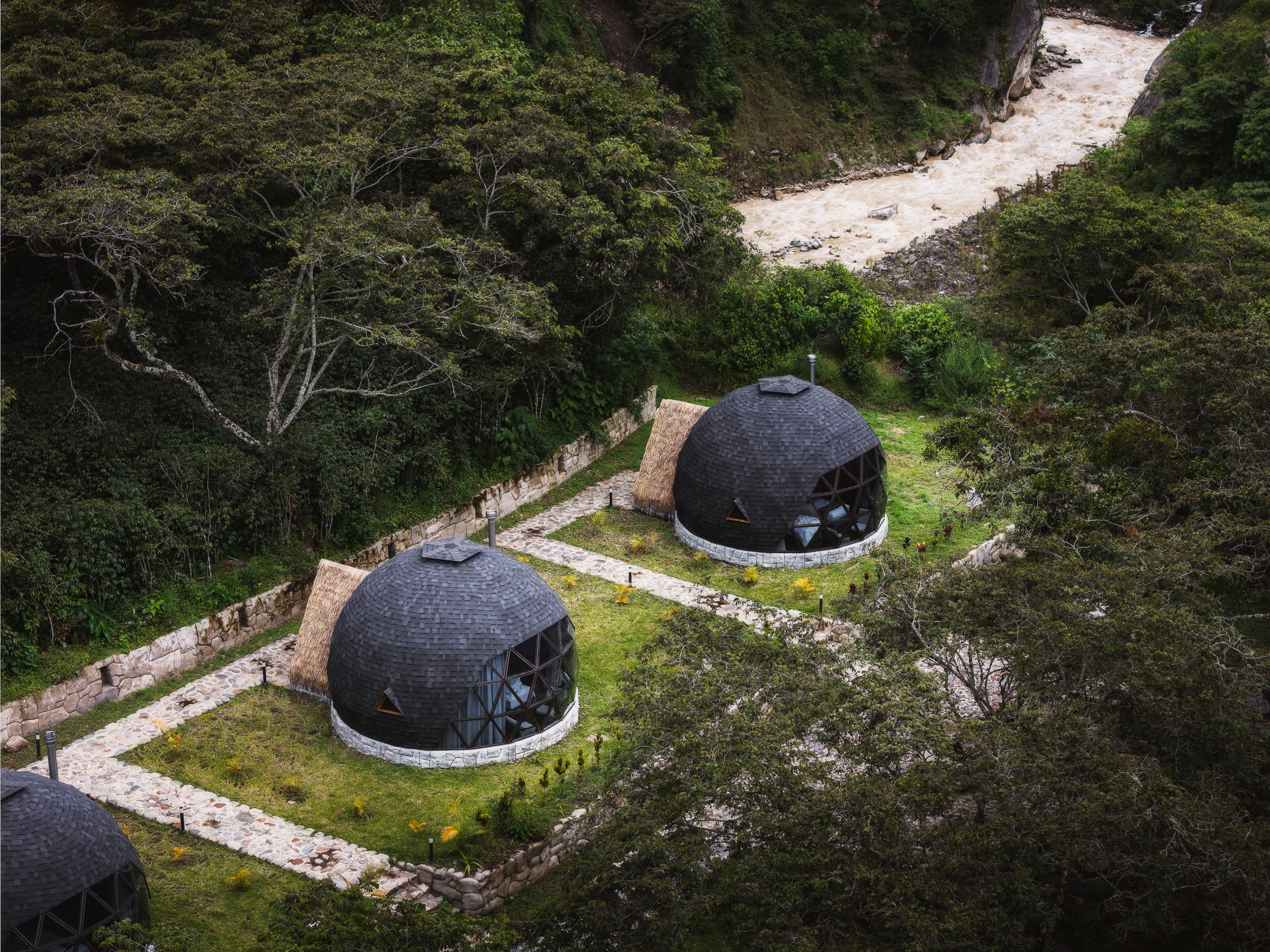 Two geodesic trekking lodges surrounded by dense mountain forest