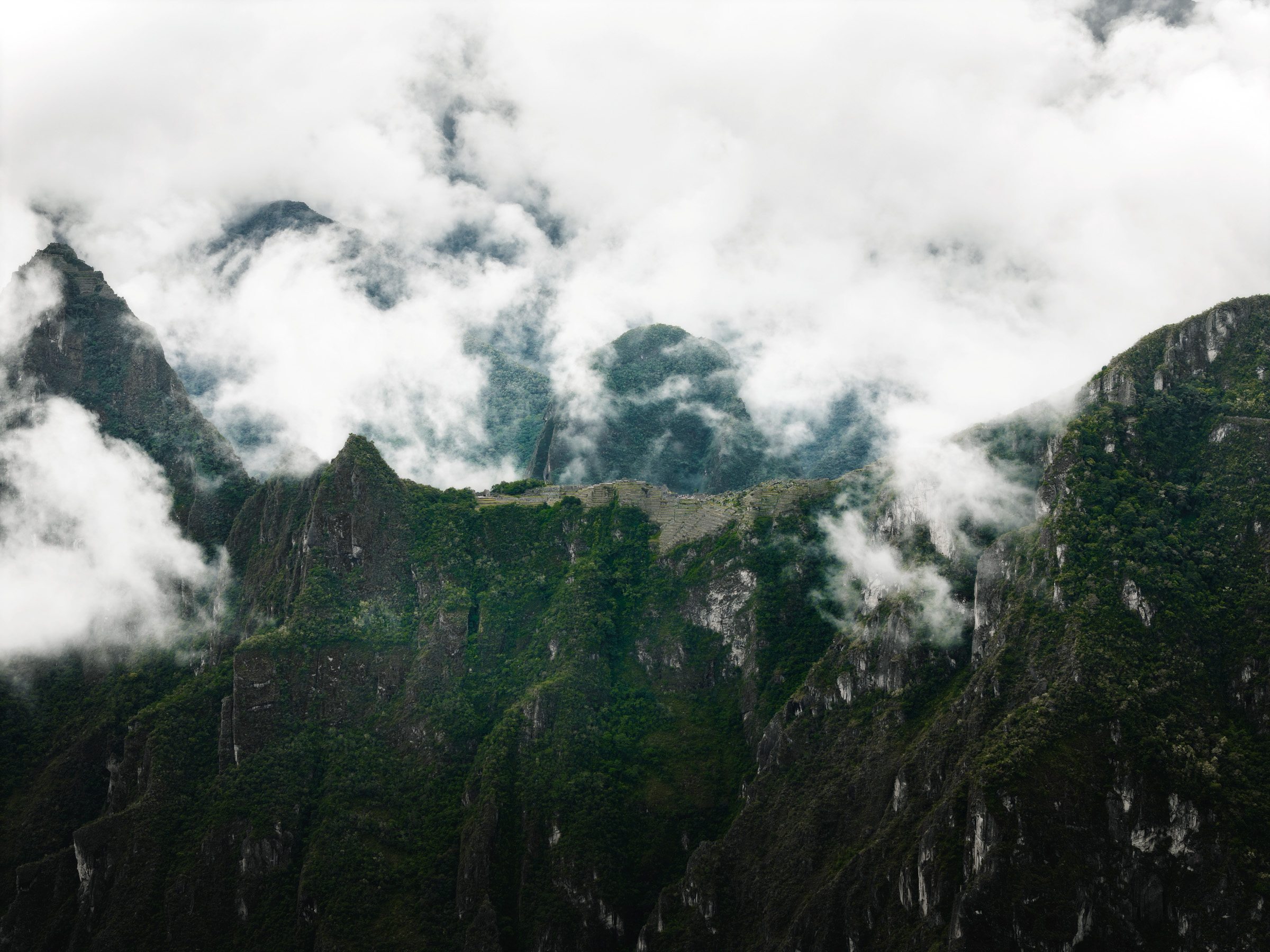 Steep green Andean ridges disappearing into low clouds