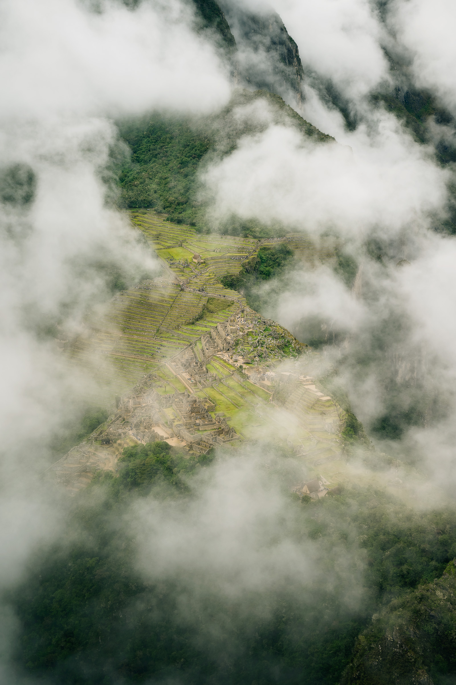Machu Picchu emerging through drifting clouds from above