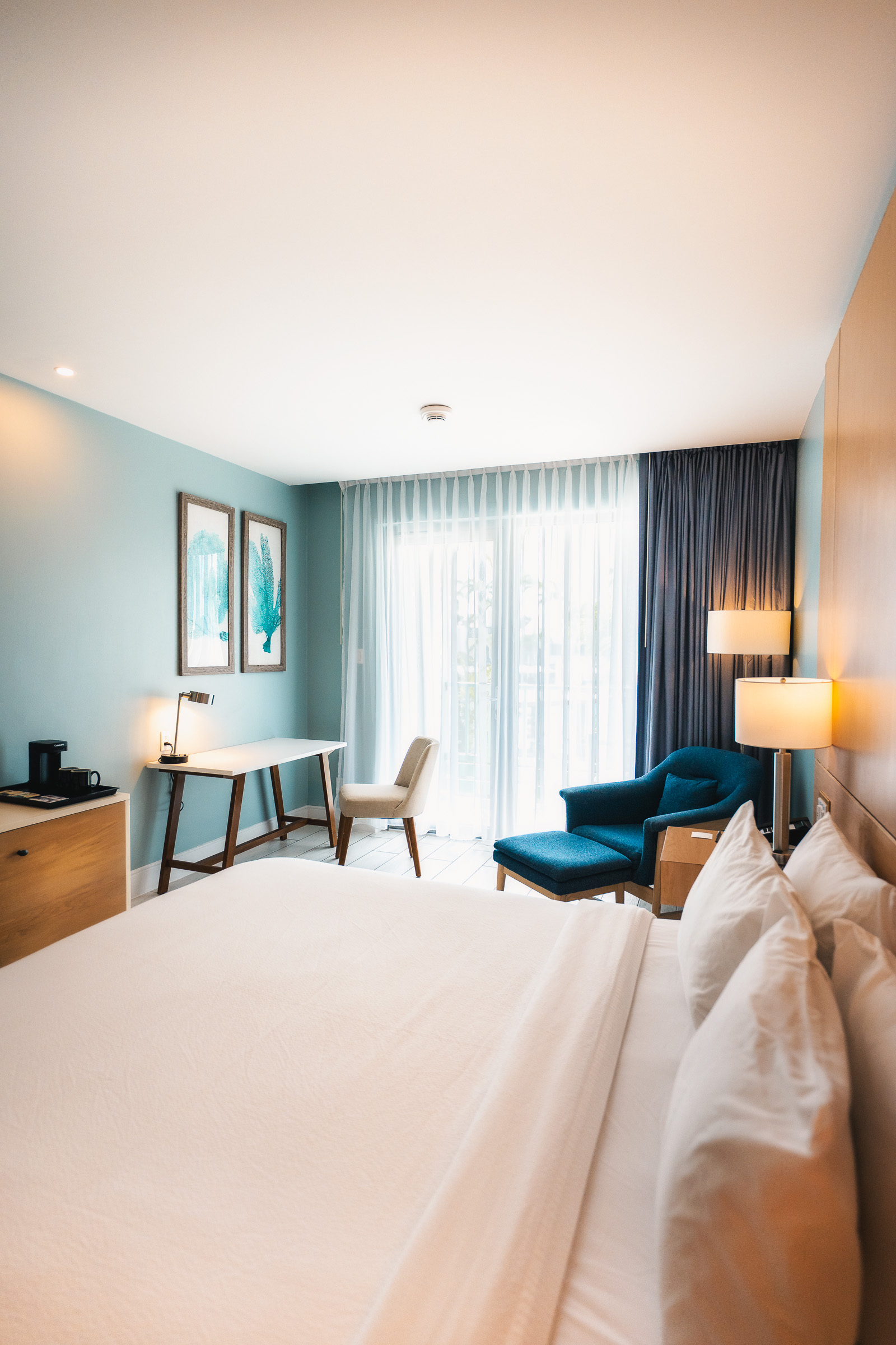 Bright guest room with a large bed and blue lounge chairs at Courtyard Aruba