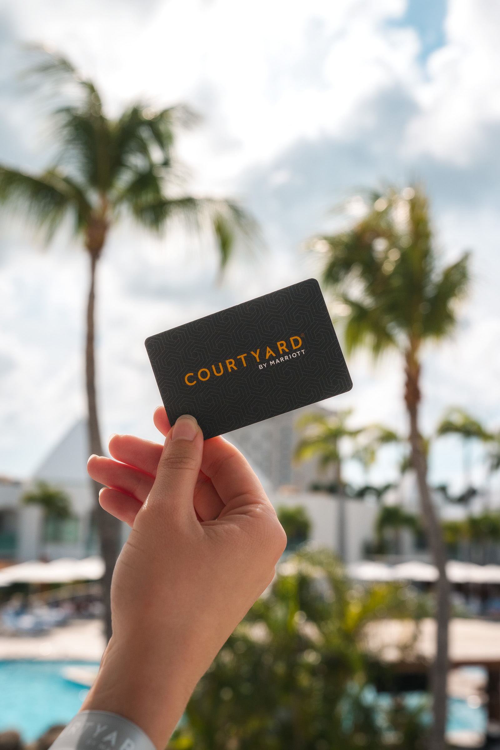 Hand holding a Courtyard hotel key card beside the pool
