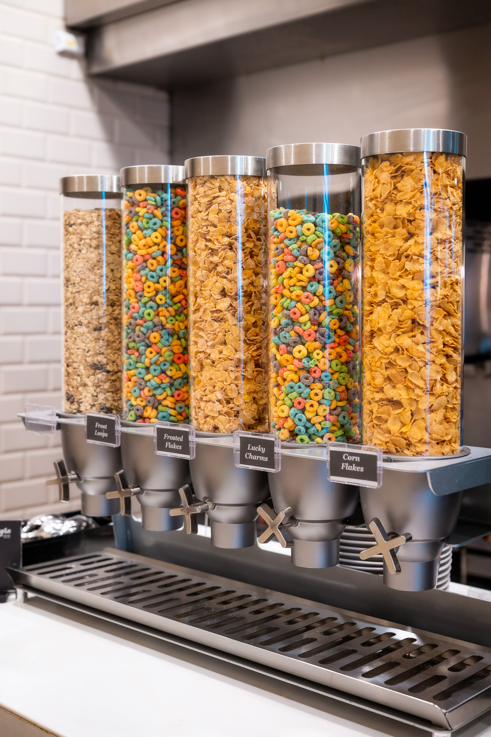 Row of colorful cereal dispensers at the hotel breakfast buffet