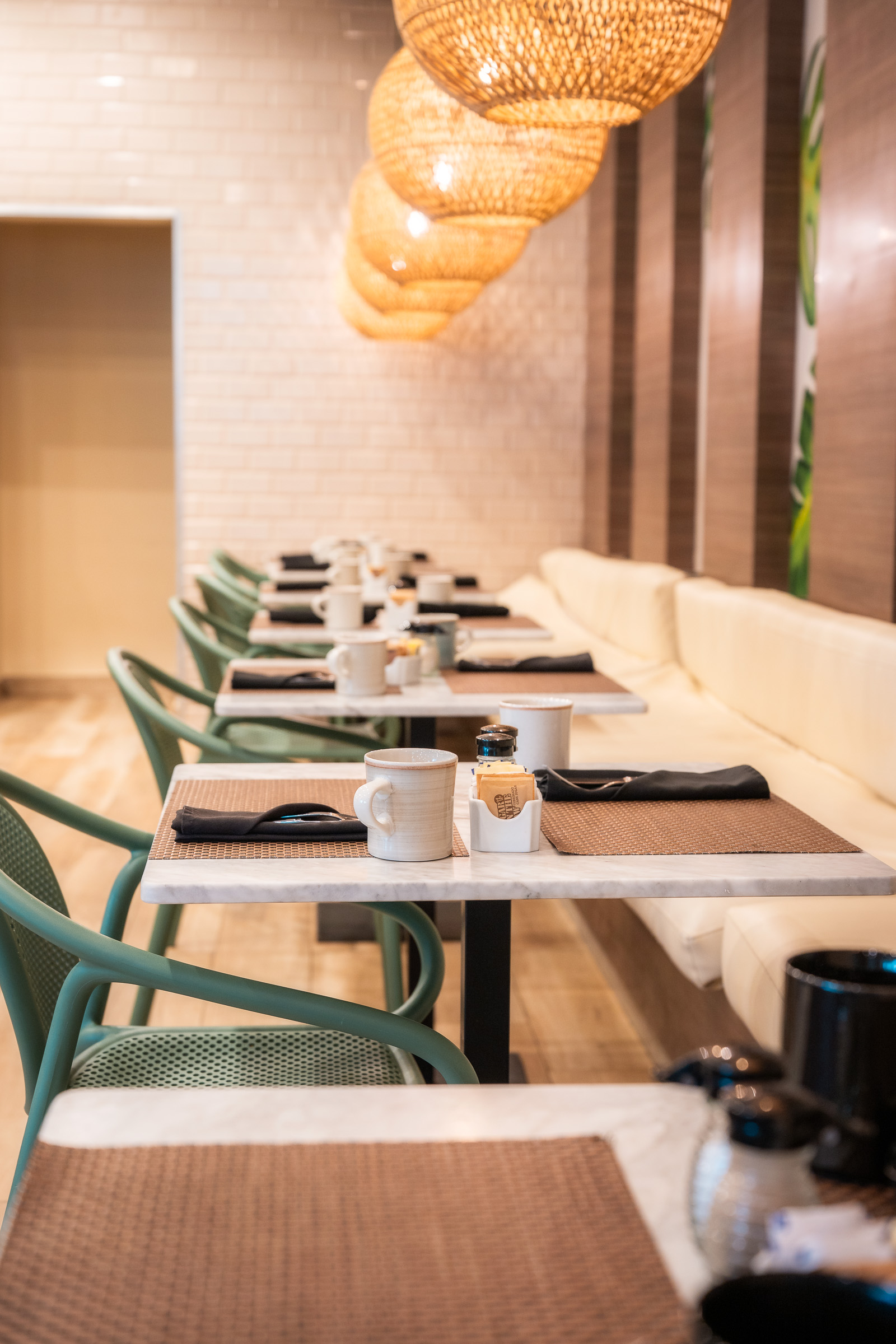 Breakfast tables set beneath woven pendant lights in the hotel restaurant