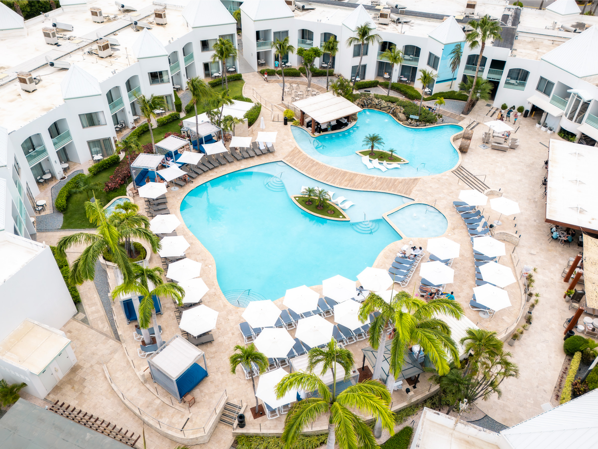 Aerial view across the curved pools and white buildings of Courtyard Aruba