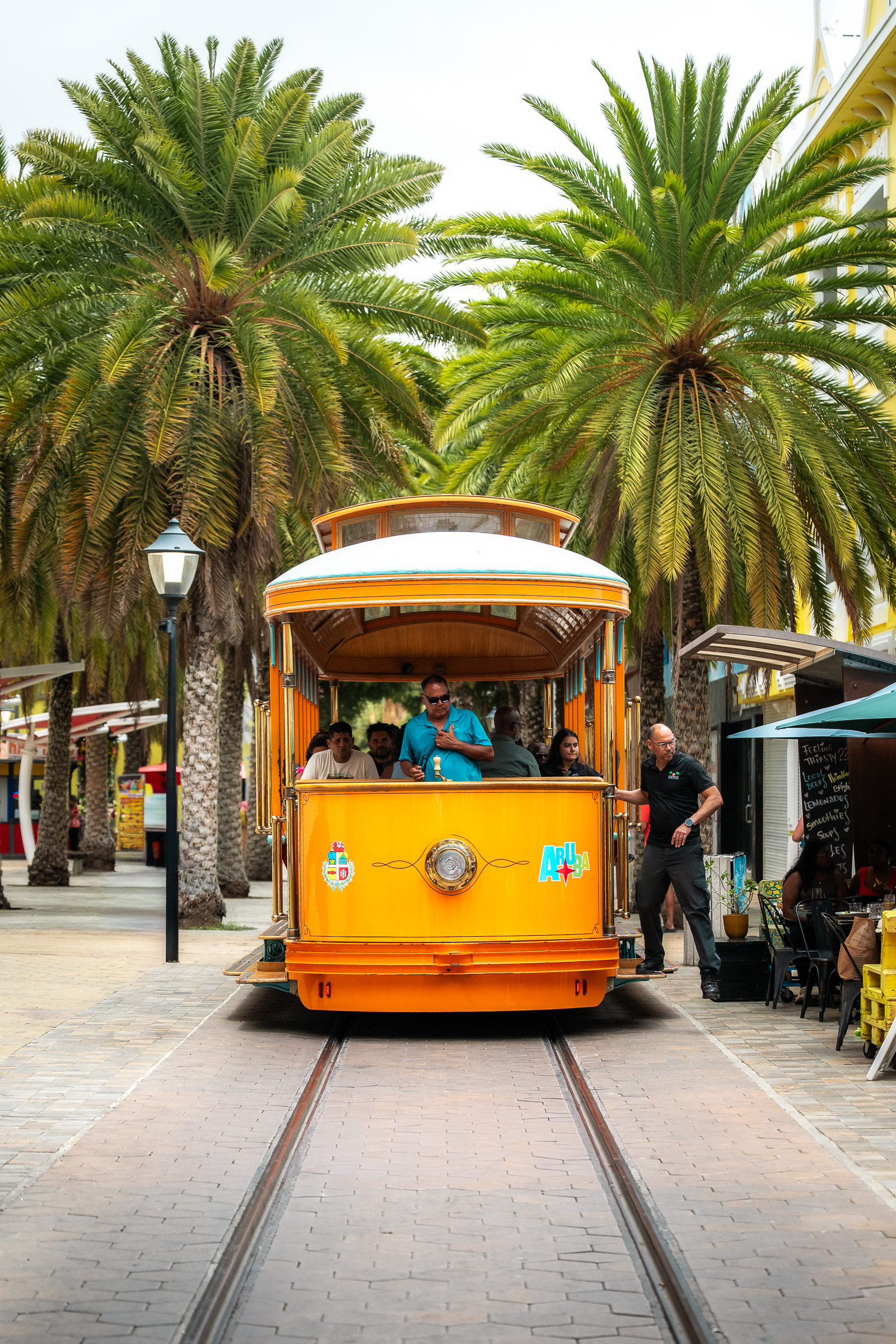 Orange streetcar on a palm-lined street in Oranjestad