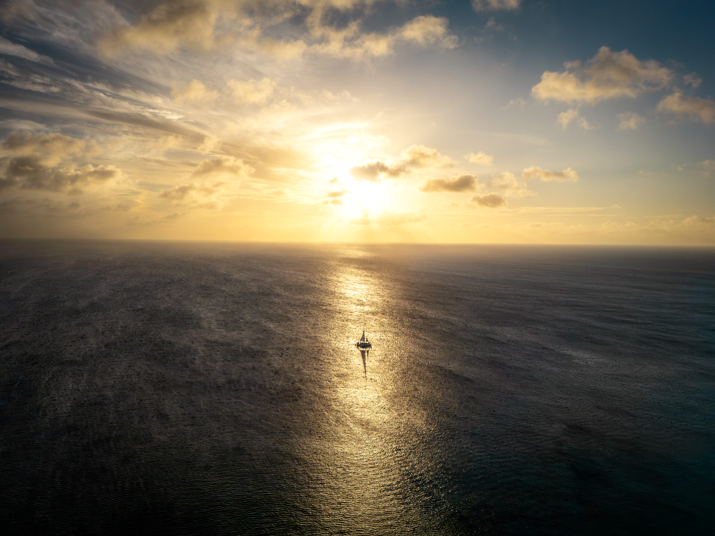 Paddleboarder crossing the sunlit Caribbean Sea at sunset