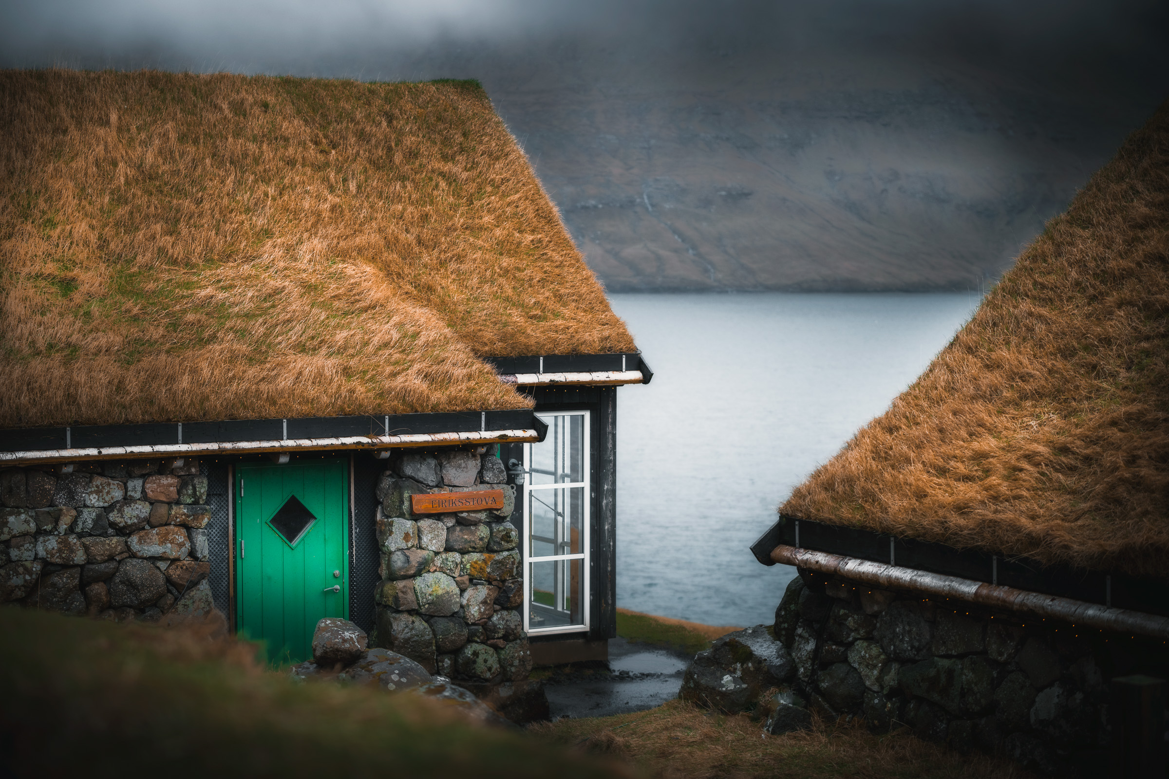 Traditionelle Häuser mit Grasdächern über einem färöischen Fjord