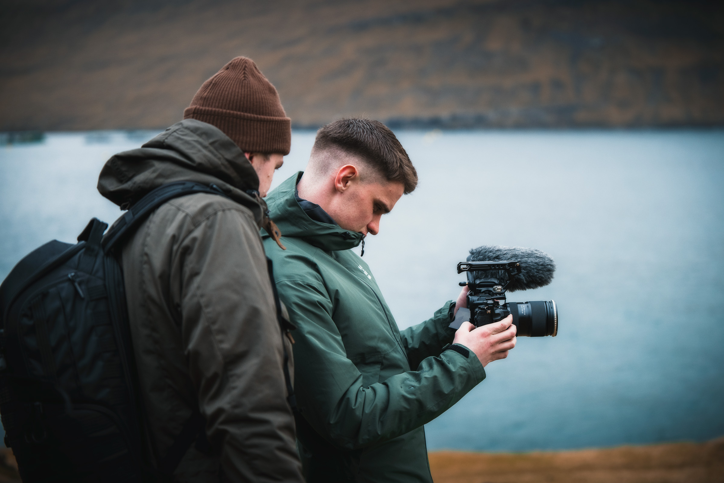 Zwei Fotografen prüfen eine Kamera an einem Bergsee