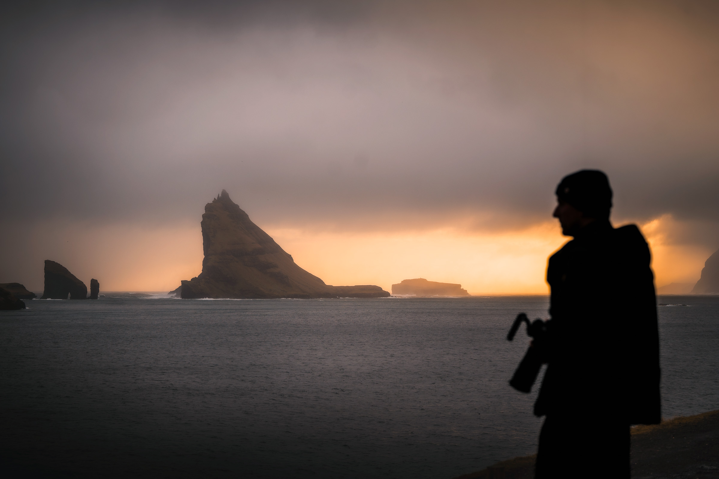 Silhouette eines Fotografen vor Tindhólmur bei Sonnenuntergang
