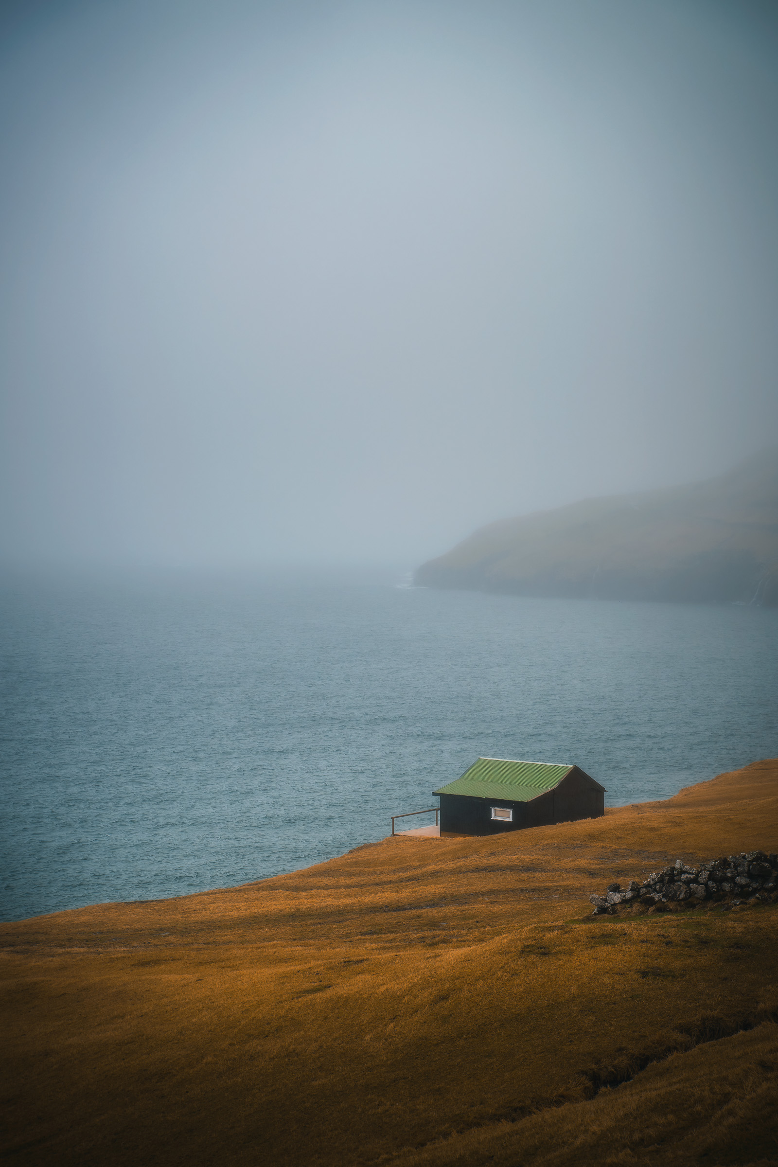 Einzelne Hütte mit Grasdach über einer nebligen Atlantikküste