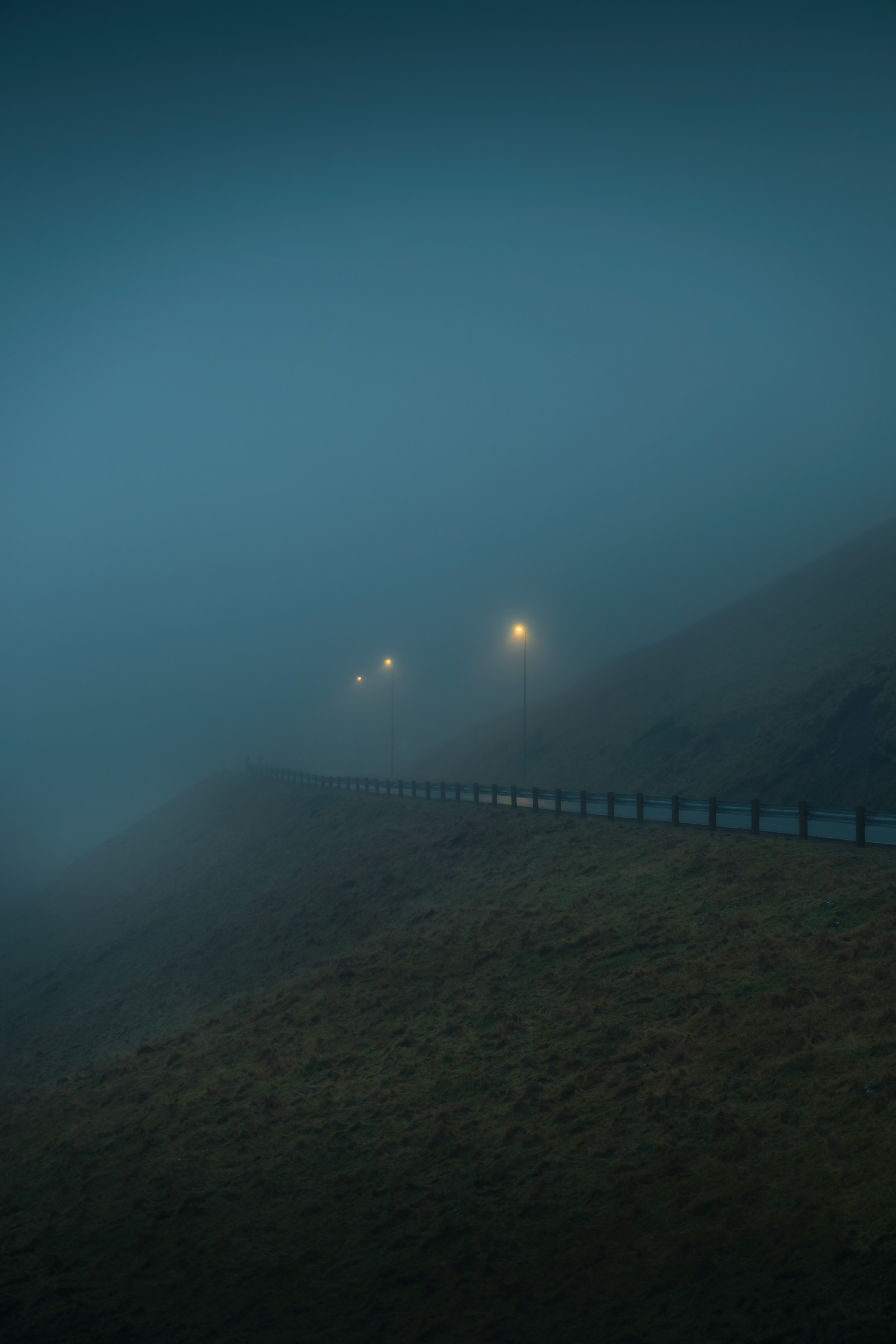 Scheinwerfer leuchten durch dichten Nebel auf einer Bergstraße