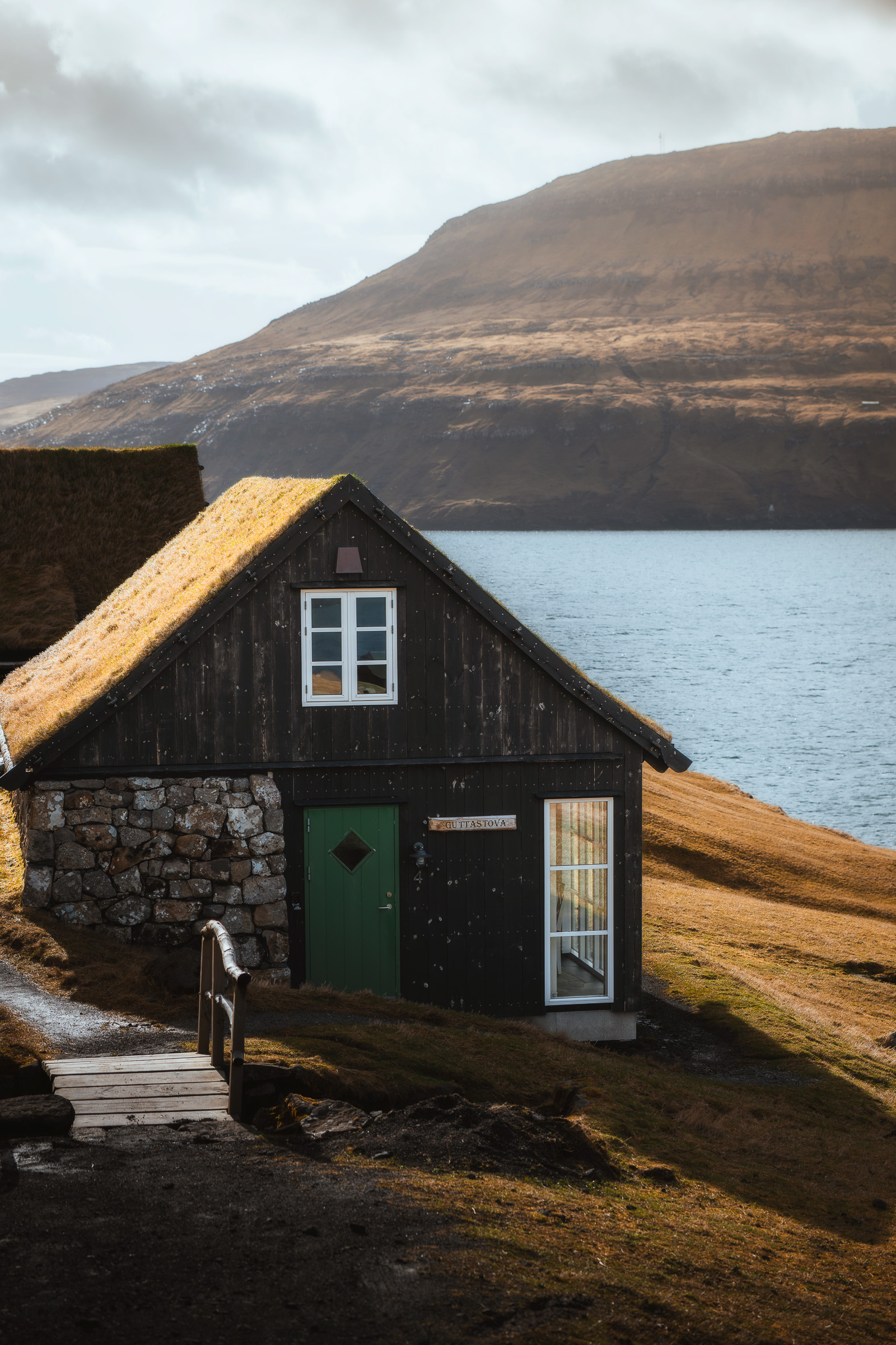 Steinhaus mit Grasdach an einem ruhigen Fjord