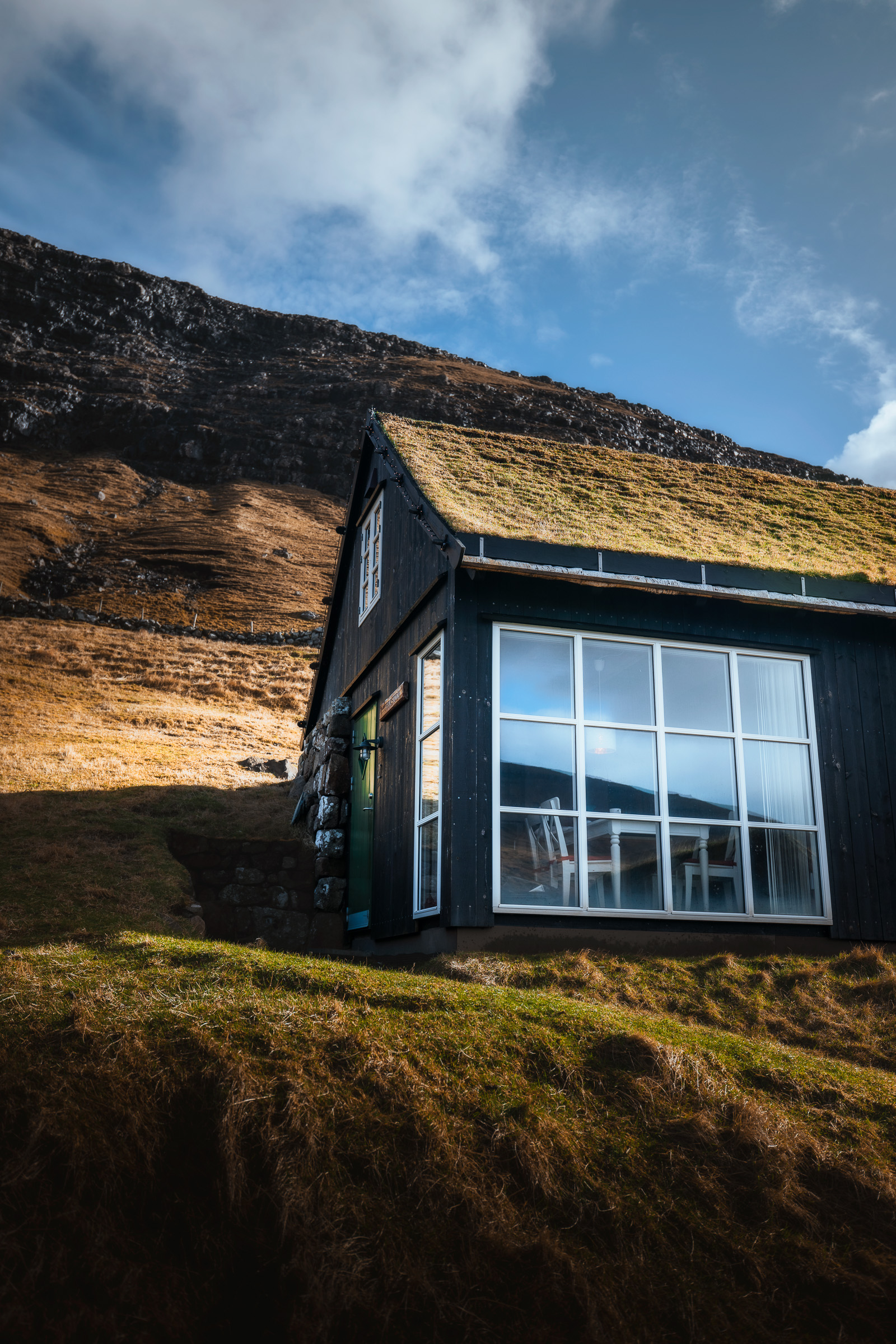 Schwarze Holzhütte mit Grasdach im herbstlichen Licht