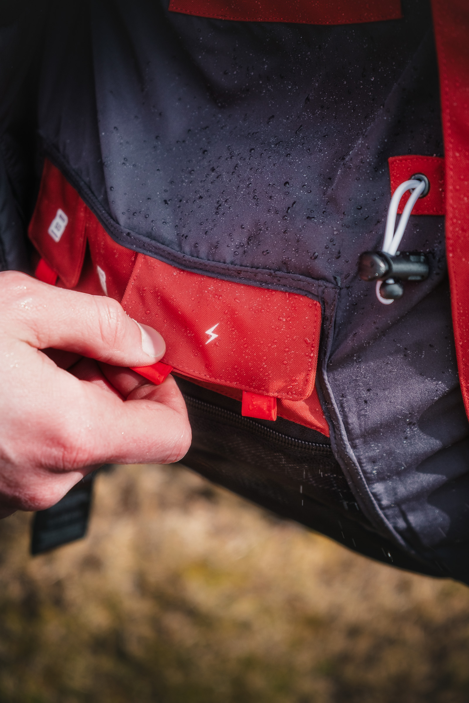 Hand schließt die Tasche einer wasserdichten Jacke