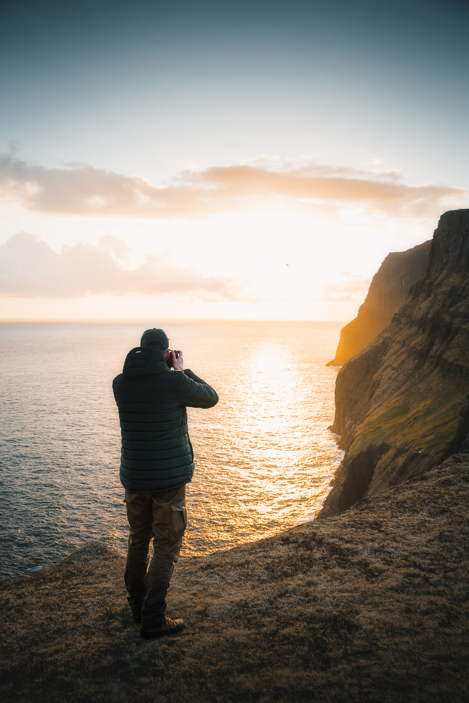 Fotograf hält den Sonnenuntergang an einem schroffen Küstenaussichtspunkt fest