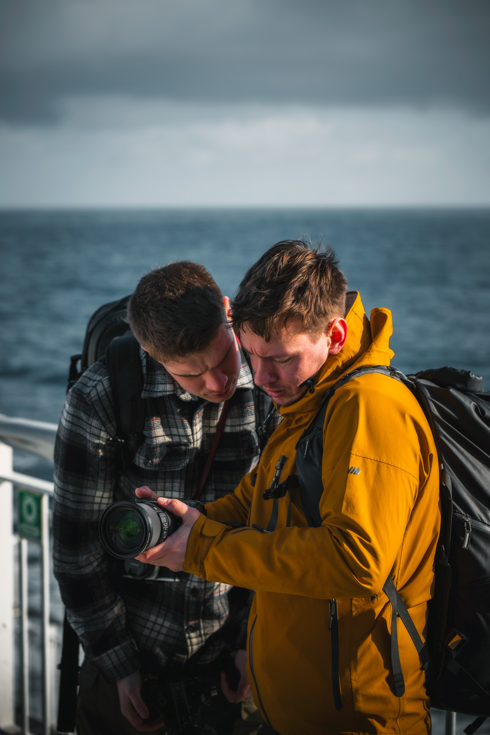 Zwei Reisende prüfen auf dem Deck einer Fähre ein Smartphone