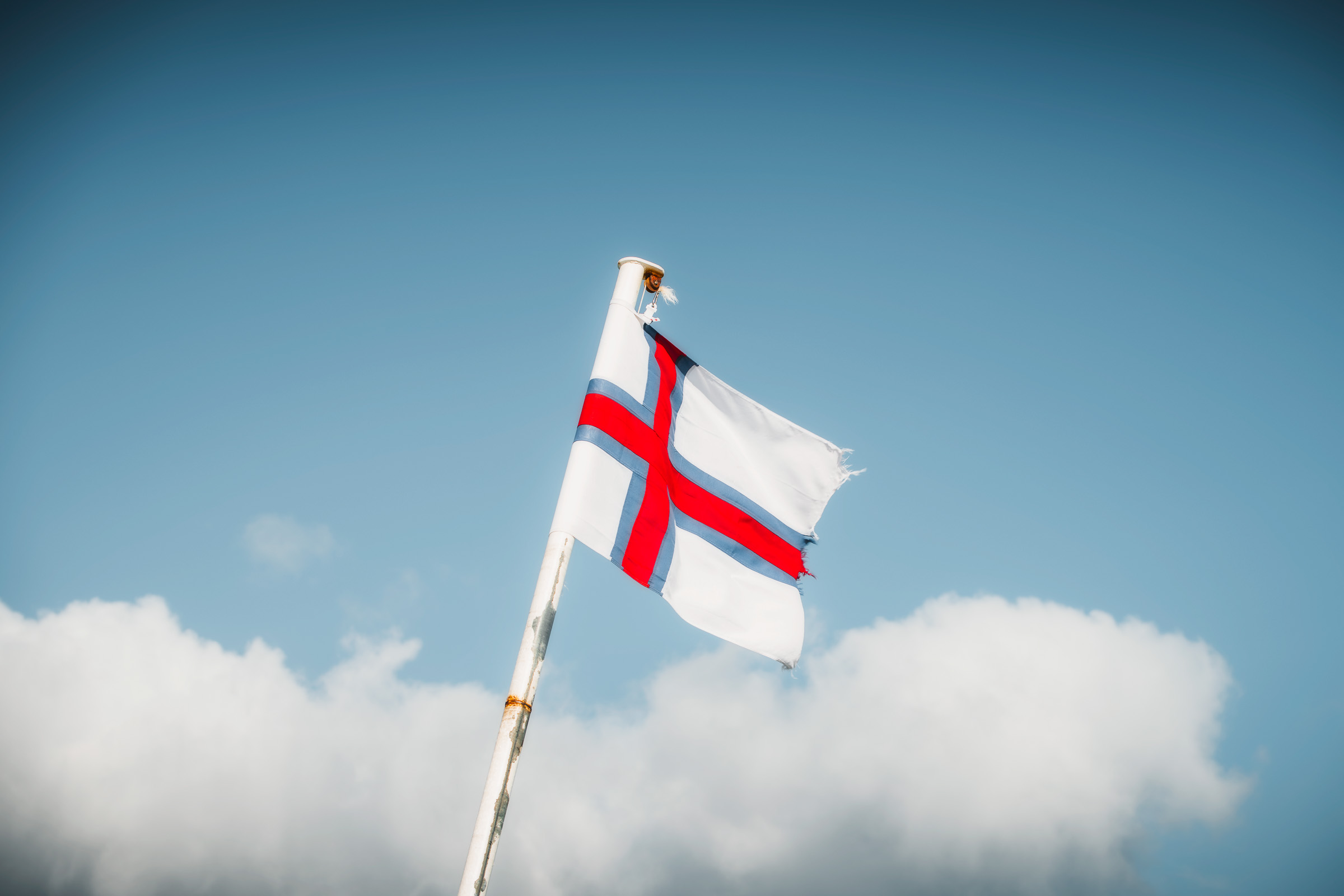 Flagge der Färöer-Inseln weht über weißen Wolken