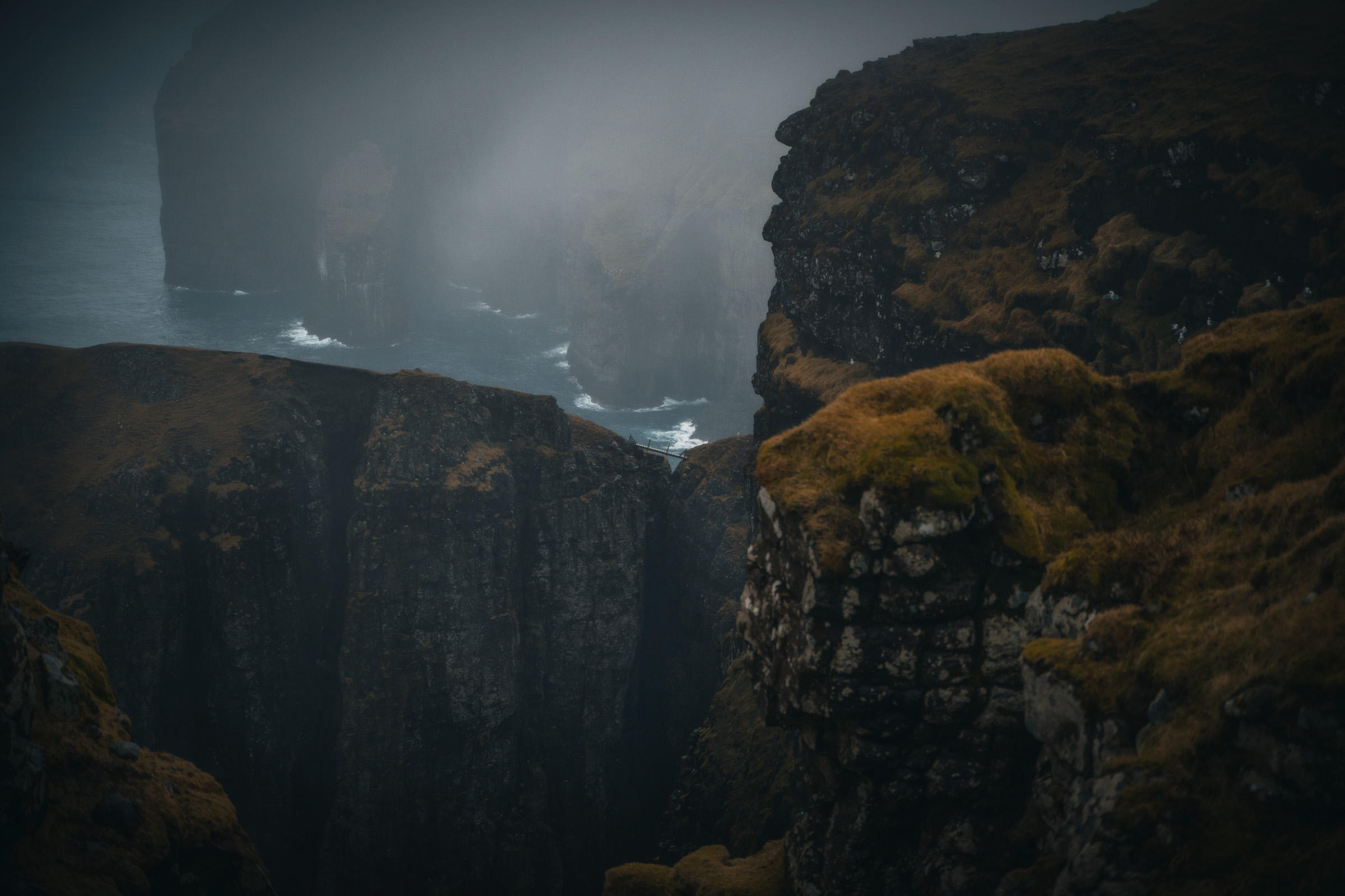 Wasserfall verschwindet zwischen dunklen Meeresklippen im Nebel