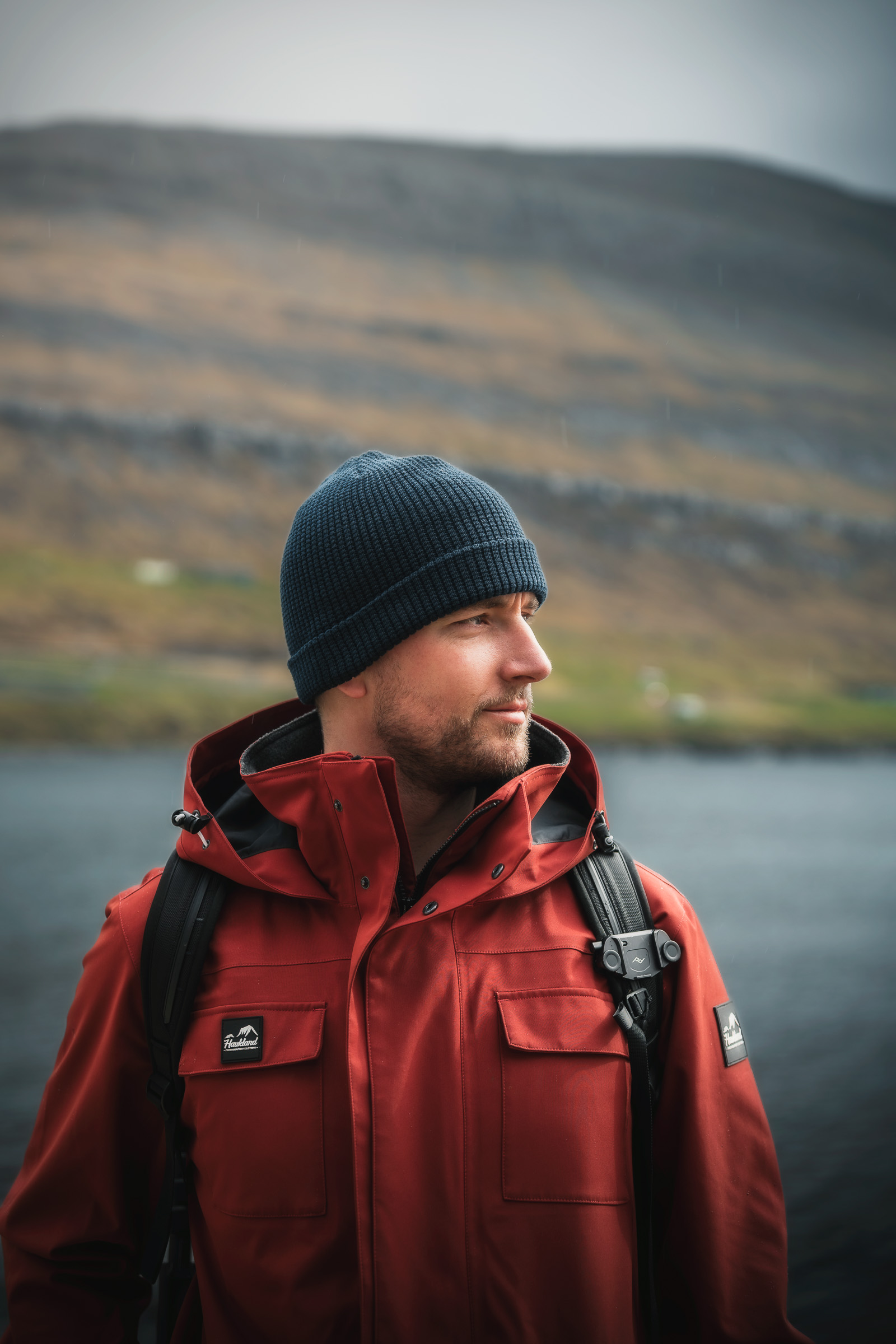 Porträt eines Reisenden in roter Jacke an einem Fjord