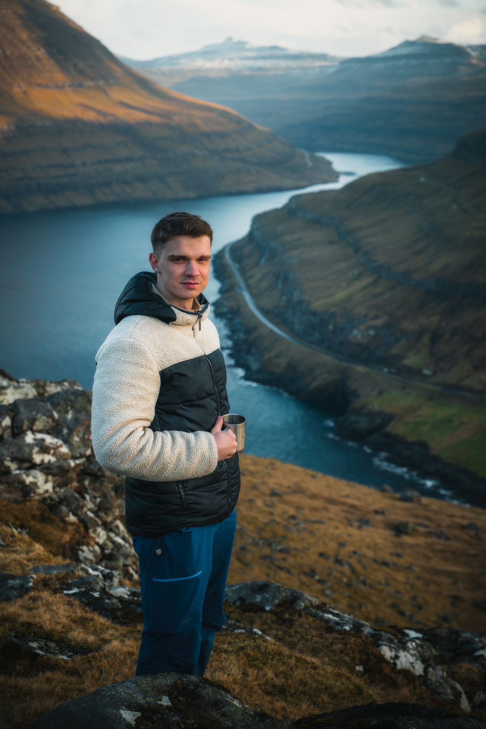 Reisender steht über einem schmalen Fjord und einem Bergdorf